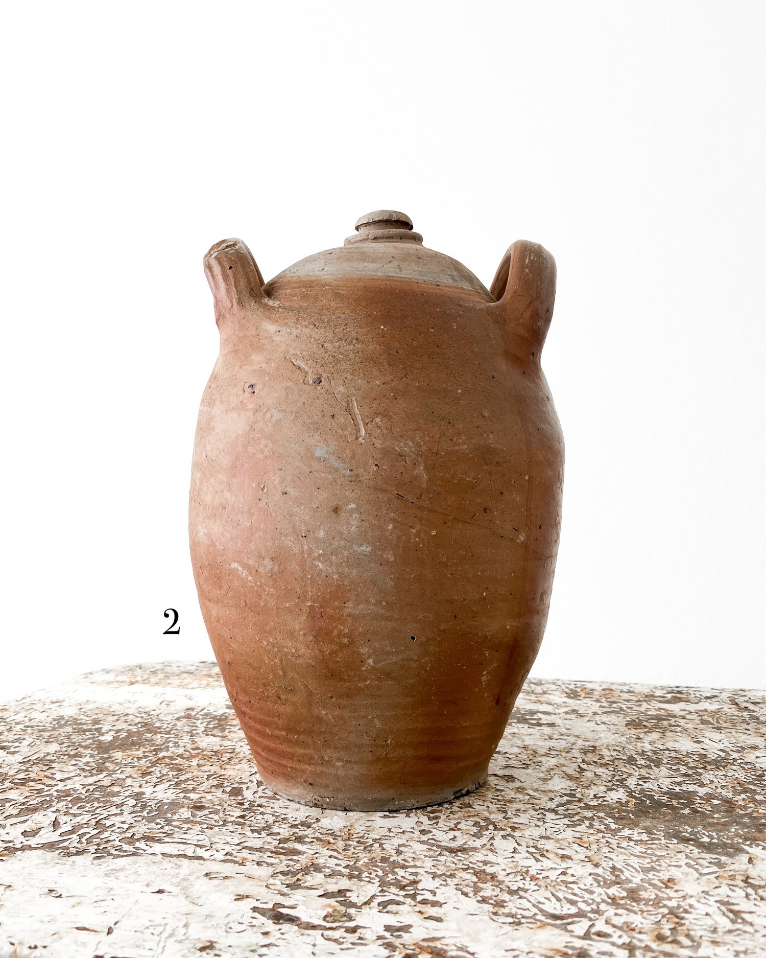 Pot on three legs, with ear, red earthenware with local brown