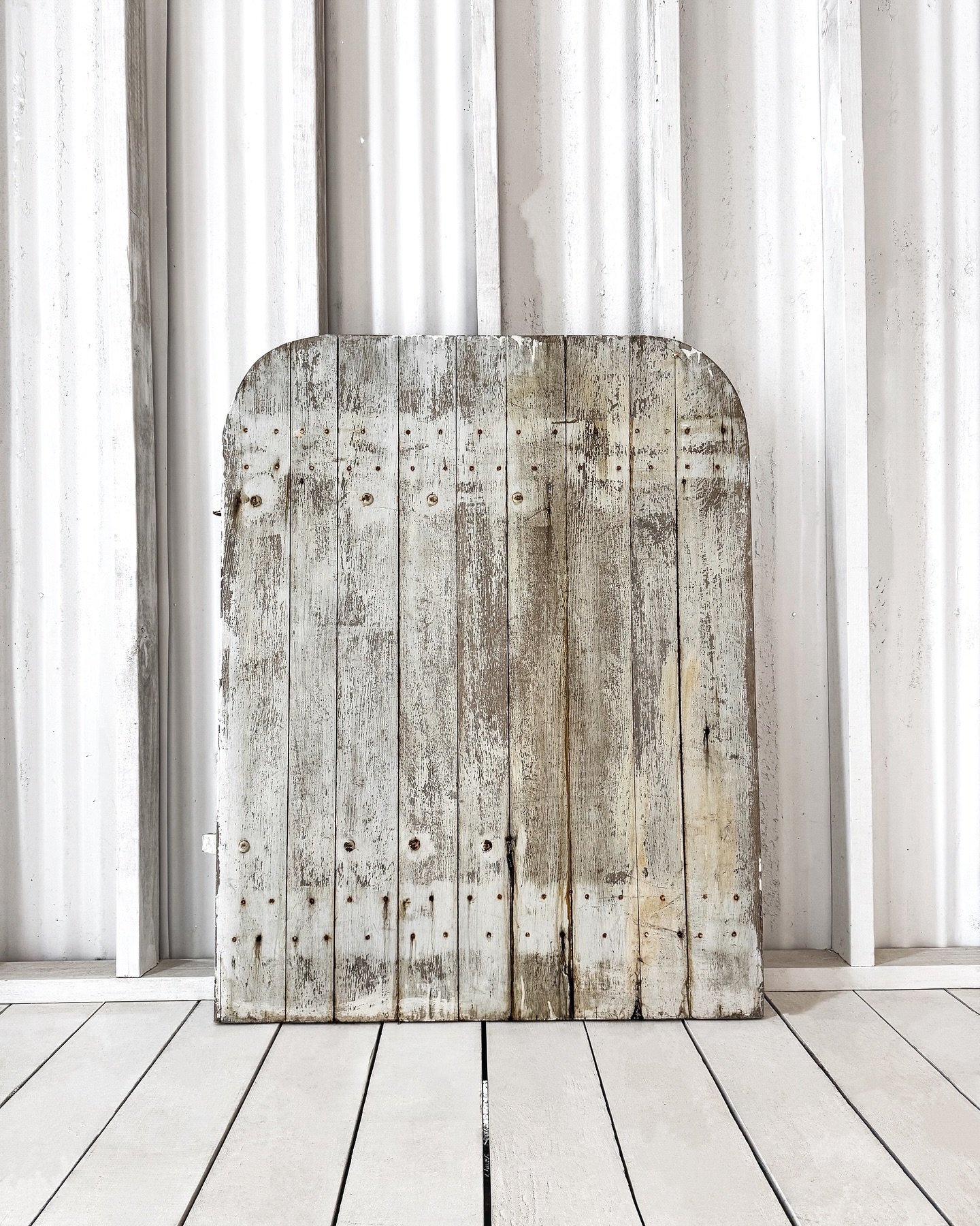 [Available] Discovered in a rustic barn nestled in the French countryside, this arched-top shutter infuses a sense of history into contemporary interiors. With its original paint and worn iron hinges, it reflects the timeless beauty that only age can
