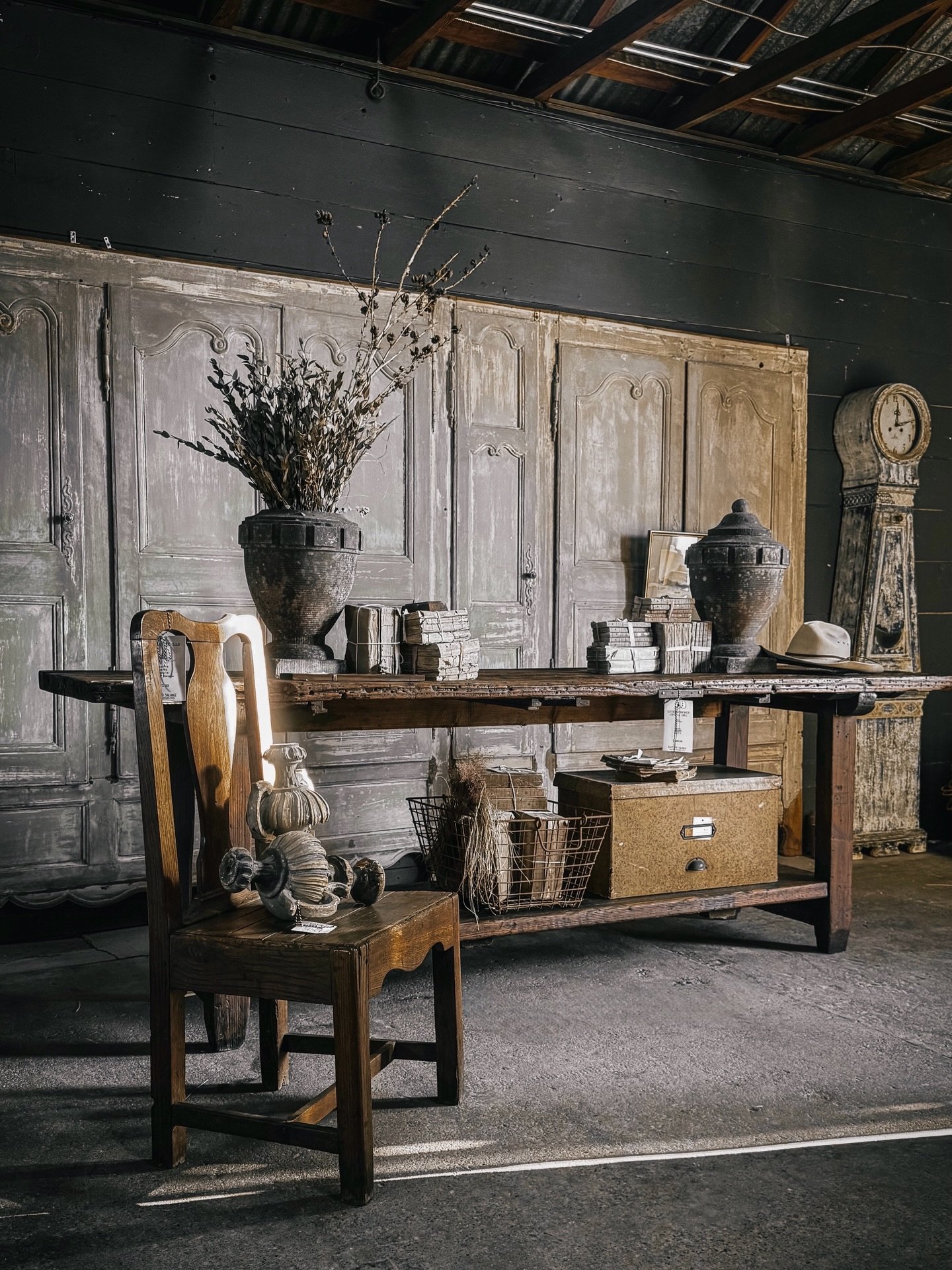 A look inside our historic barn, showcasing the last remaining treasures from this year&rsquo;s collection.

A rustic workbench, once used in a leather workshop in France, serves as a unique console, flanked by hand-carved bluestone urns. Bundles of 