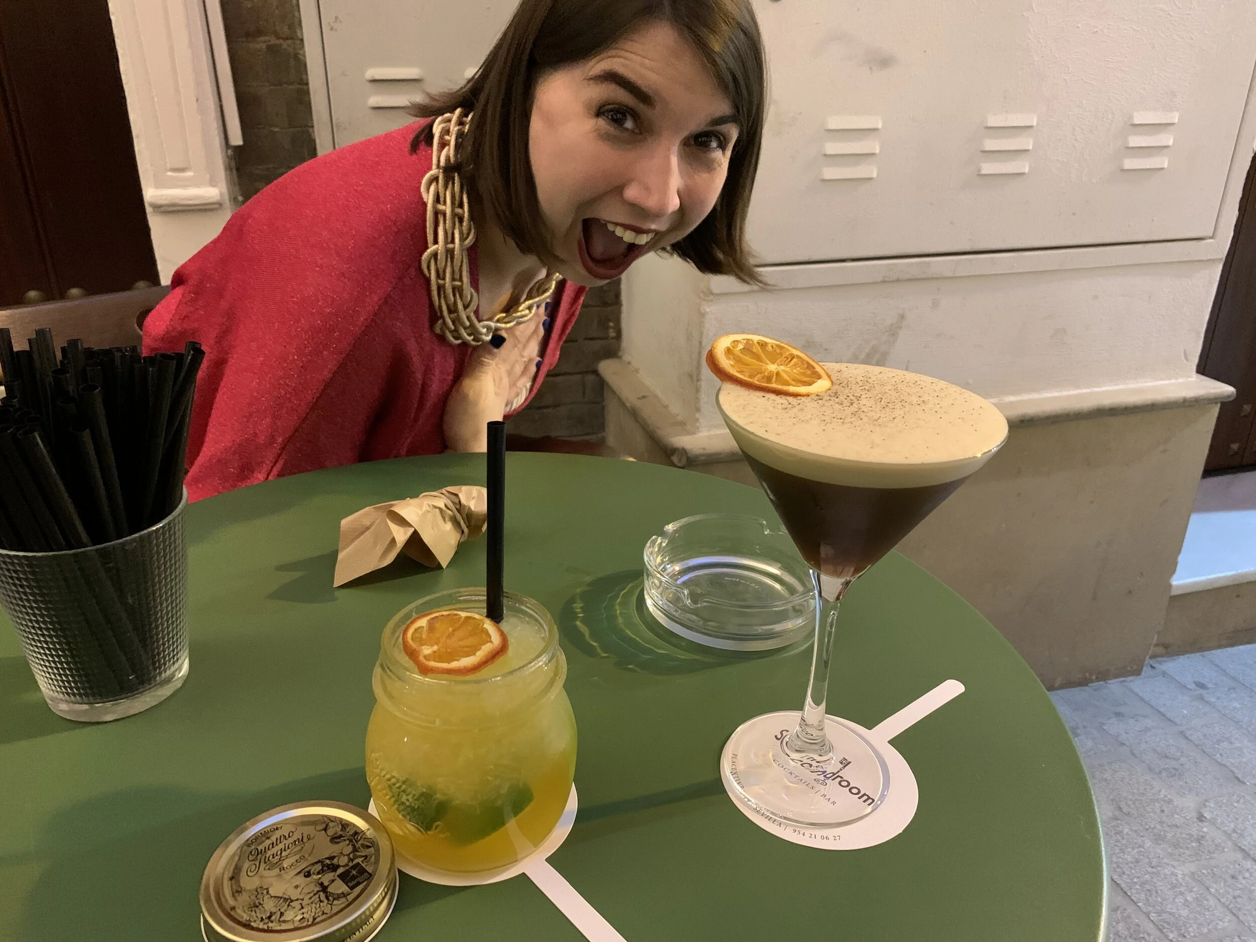 Kathryn on holiday in Sevilla for her birthday, in front of her are two cocktails (one is her husband's honest) Kathryn is wearing a sparkly dark pink top and a MEGA rose gold necklace