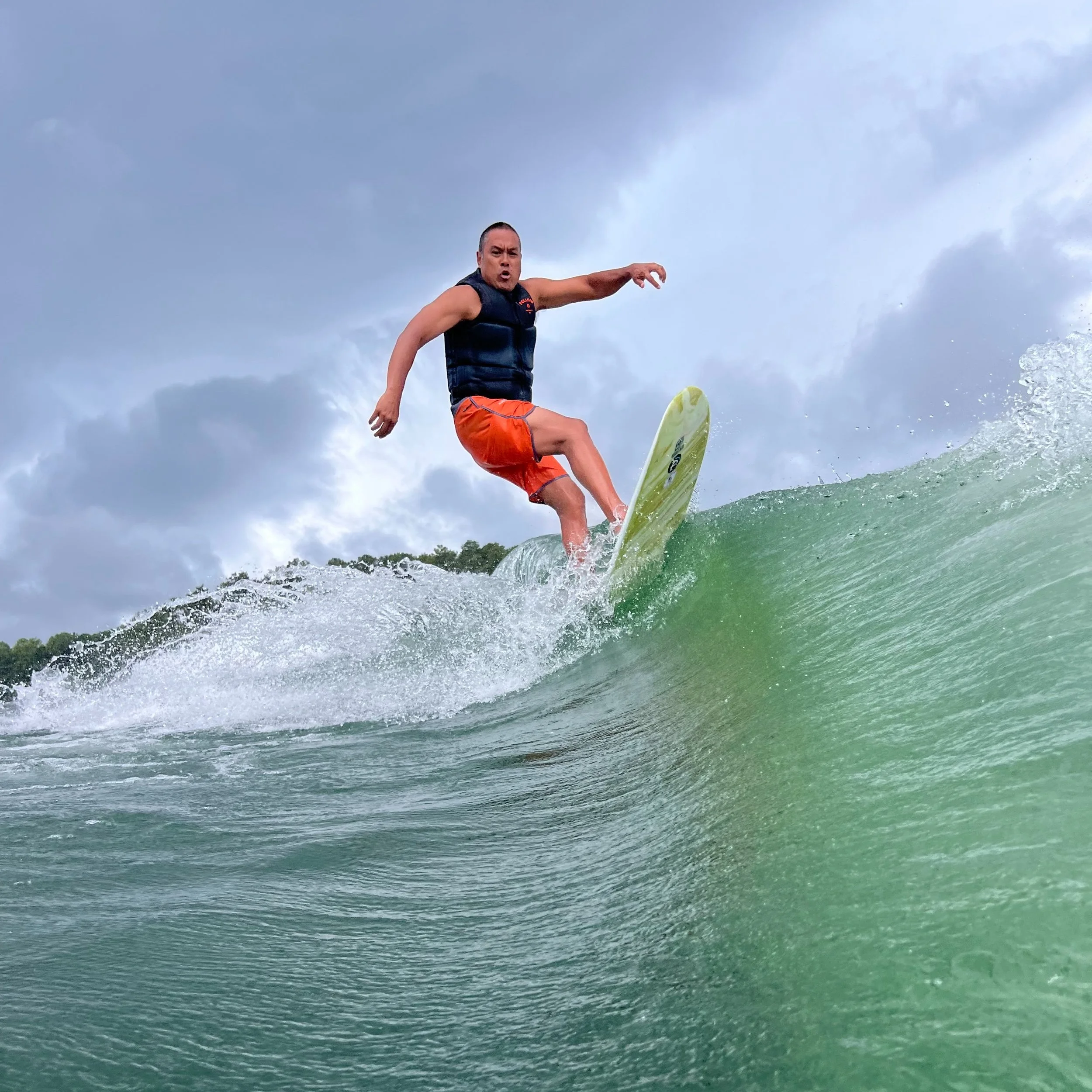 Erik rides the top of a wave on his custom Barrette surf board