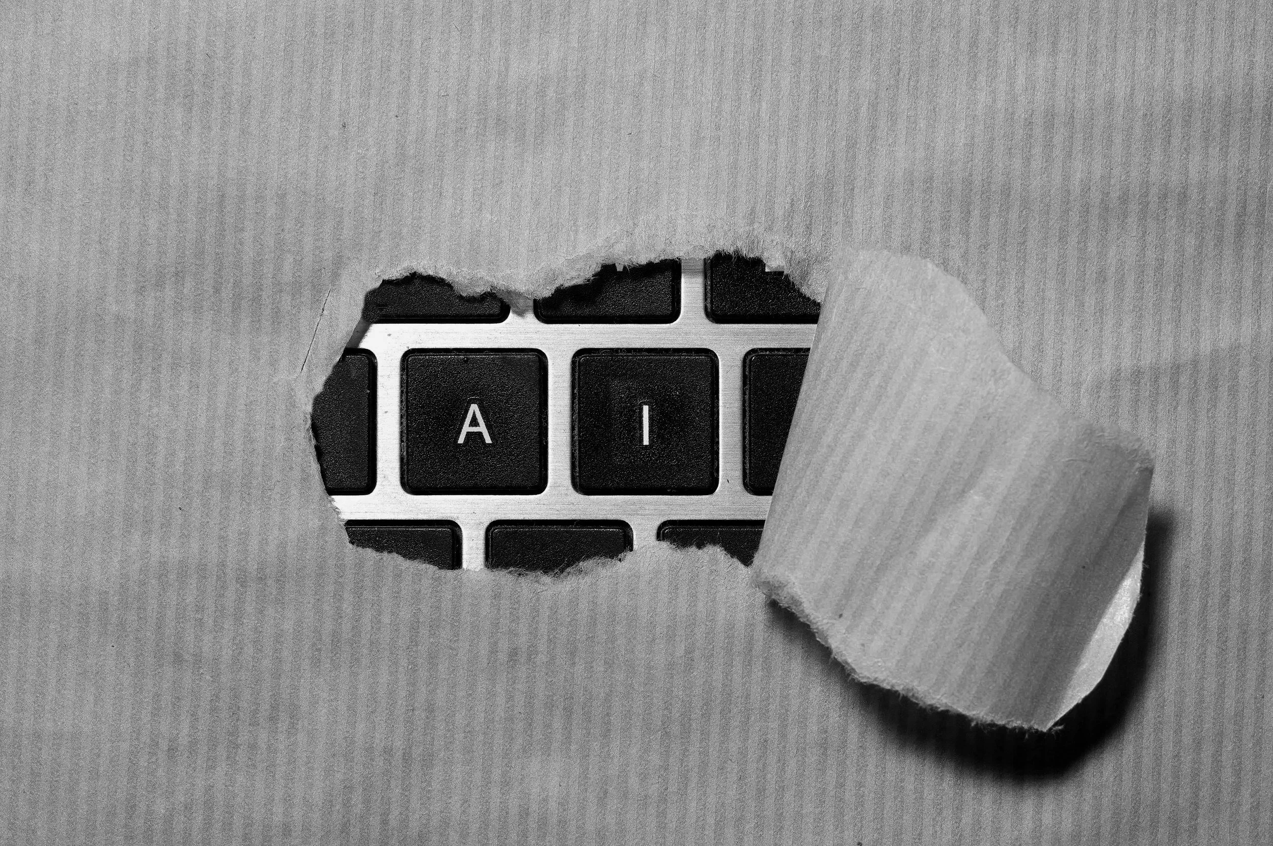 A hole in paper revealing a keyboard with the letters 'AI' on two keys.