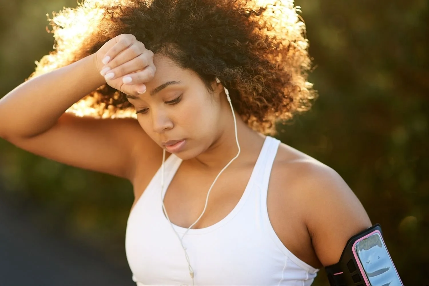 Woman pausing during a workout and holding the back of her hand to her forehead after exercise.