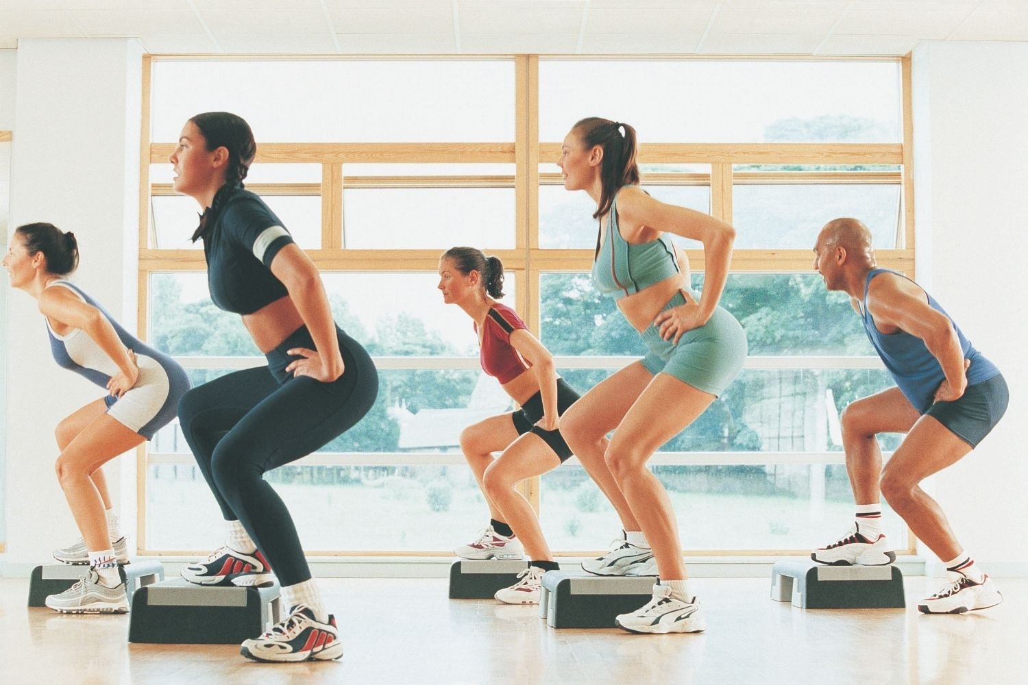 Group performing step aerobics on raised platforms in a fitness studio