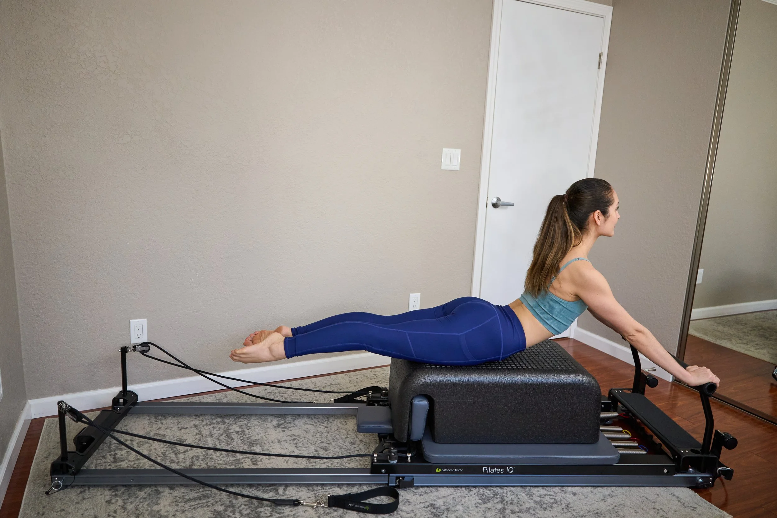 Pilates instructor performing the Swan on a Balanced Body Pilates Reformer machine