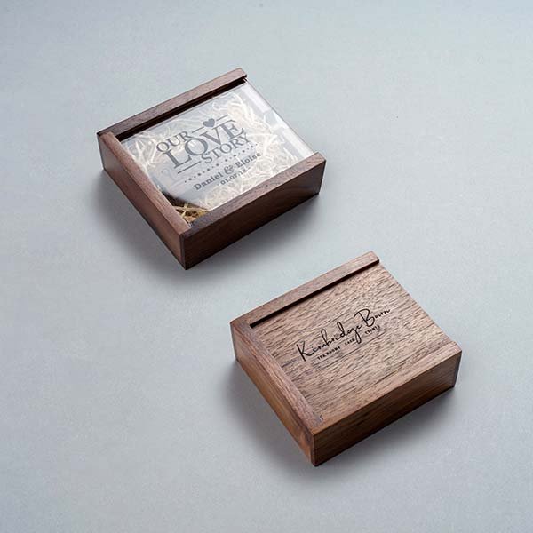 Two wooden boxes, one with a clear cover showing a card titled "Our Love Story," and the other with a handwritten message on the lid.