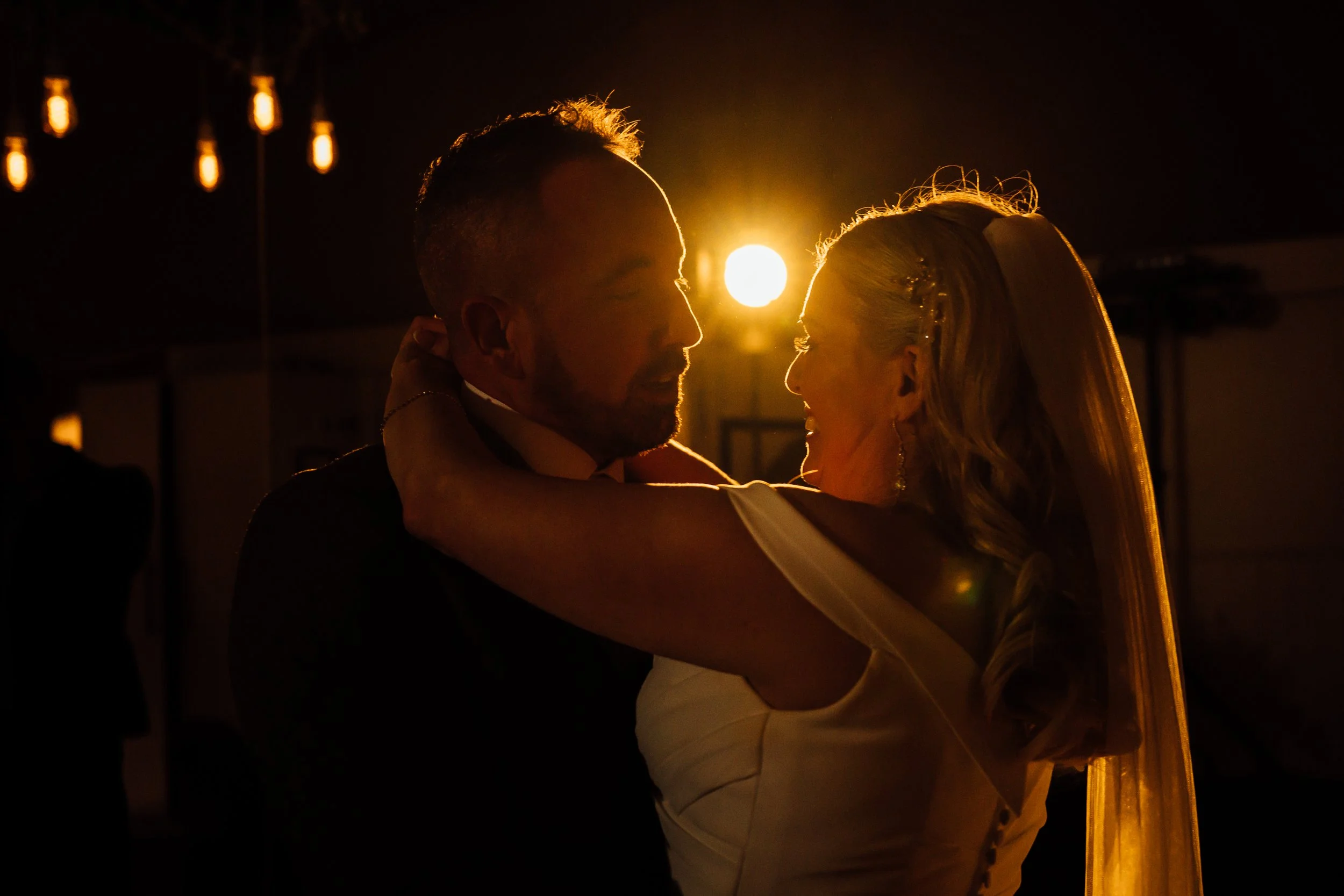A bride and groom sharing a dance at sunset during their wedding reception.