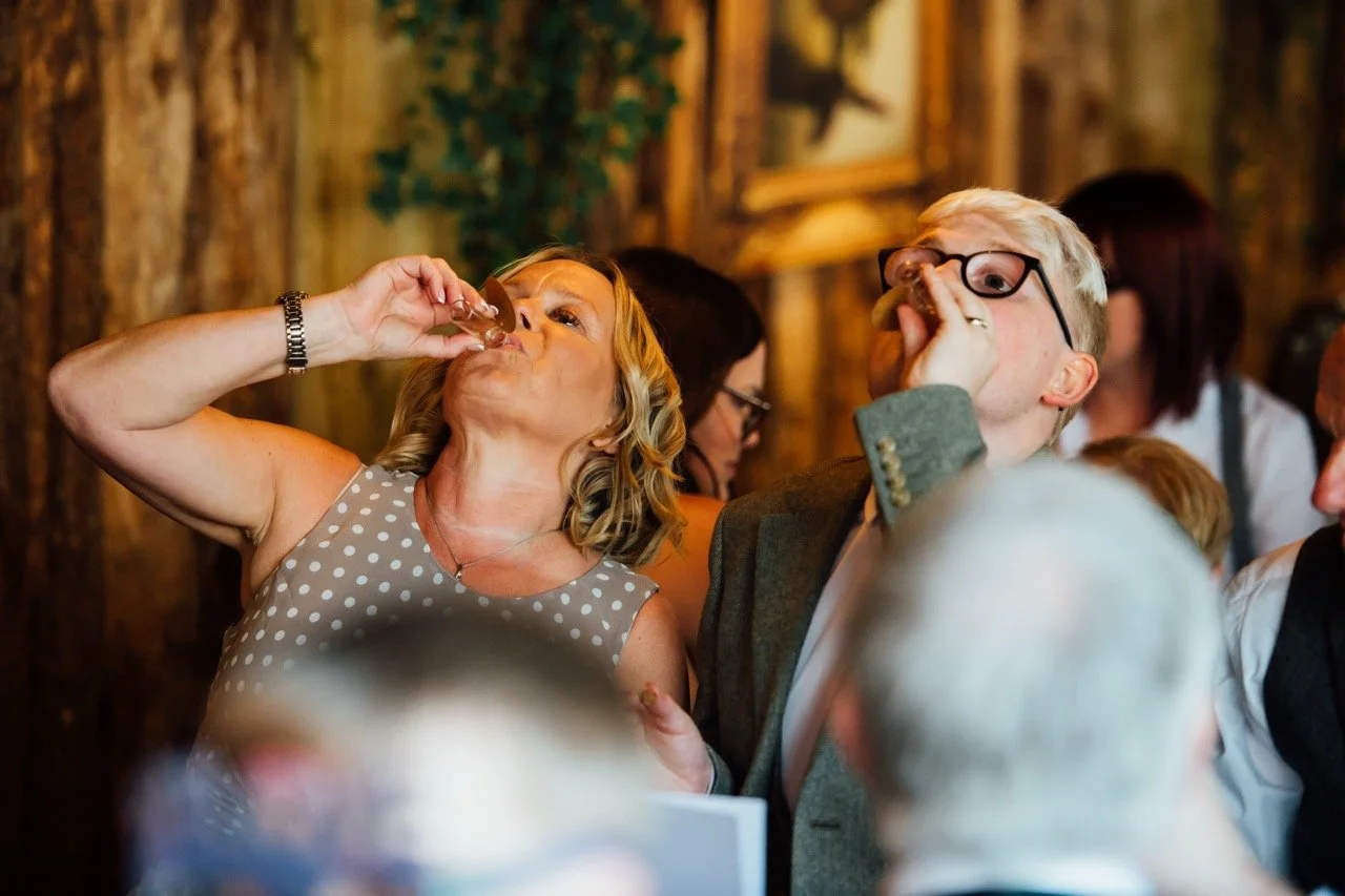 People at a social gathering drinking from small bottles.