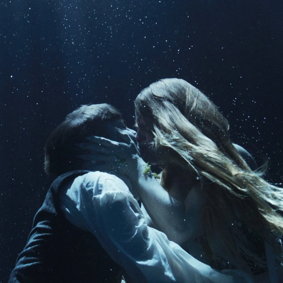 Underwater cinematography still of two performers in an emotional embrace, shot in studio tank for Oil and Water, Bus Stop Films, directed of photography by Woody Spark
