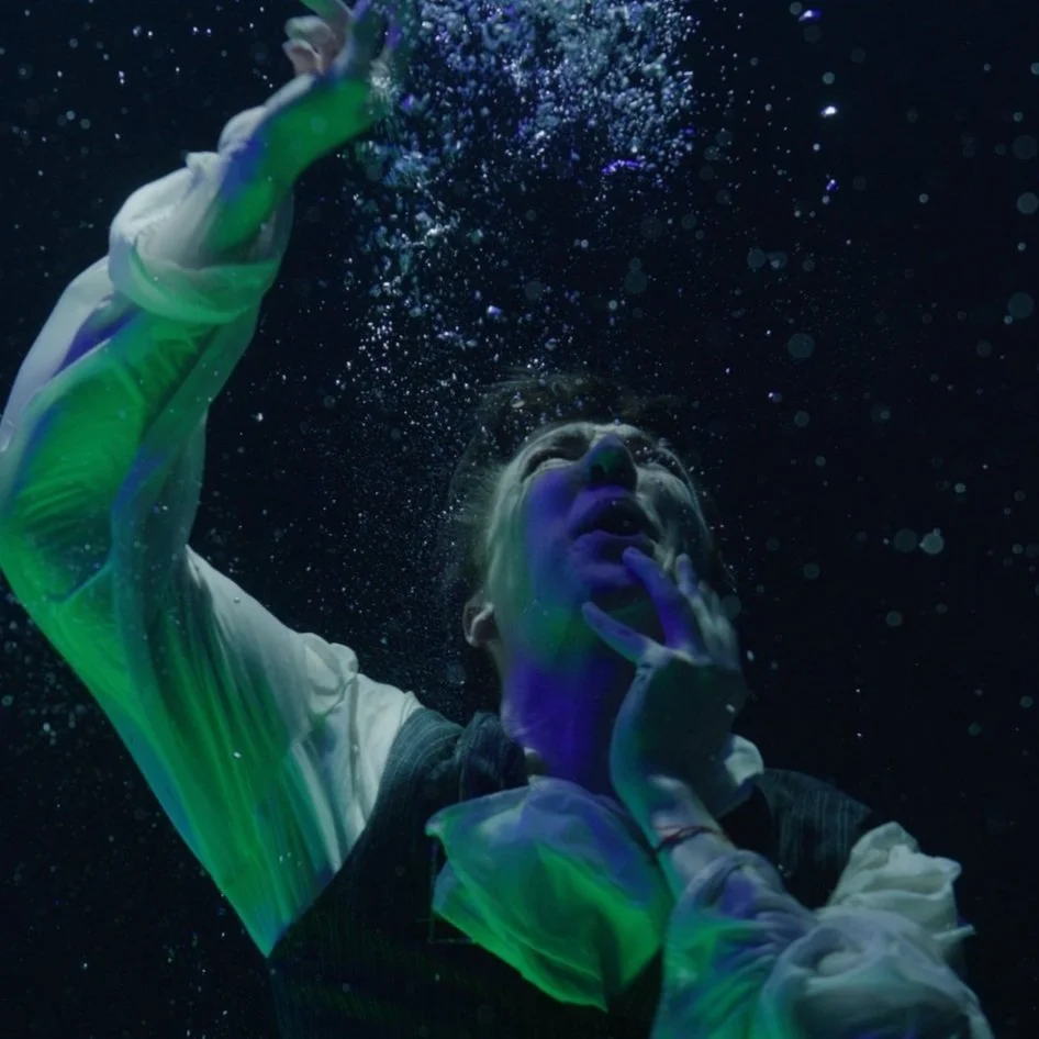 Underwater portrait with coloured lighting design, performer lit in green and blue tones, Oil and Water film, underwater DOP Woody Spark