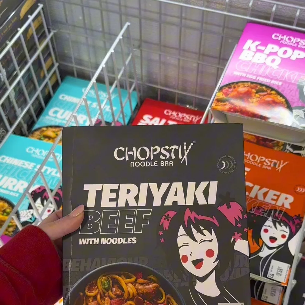 A Chopstix Teriyaki Beef ready meal held up over a basket of the Chopstix range in a Food Warehouse freezer aisle