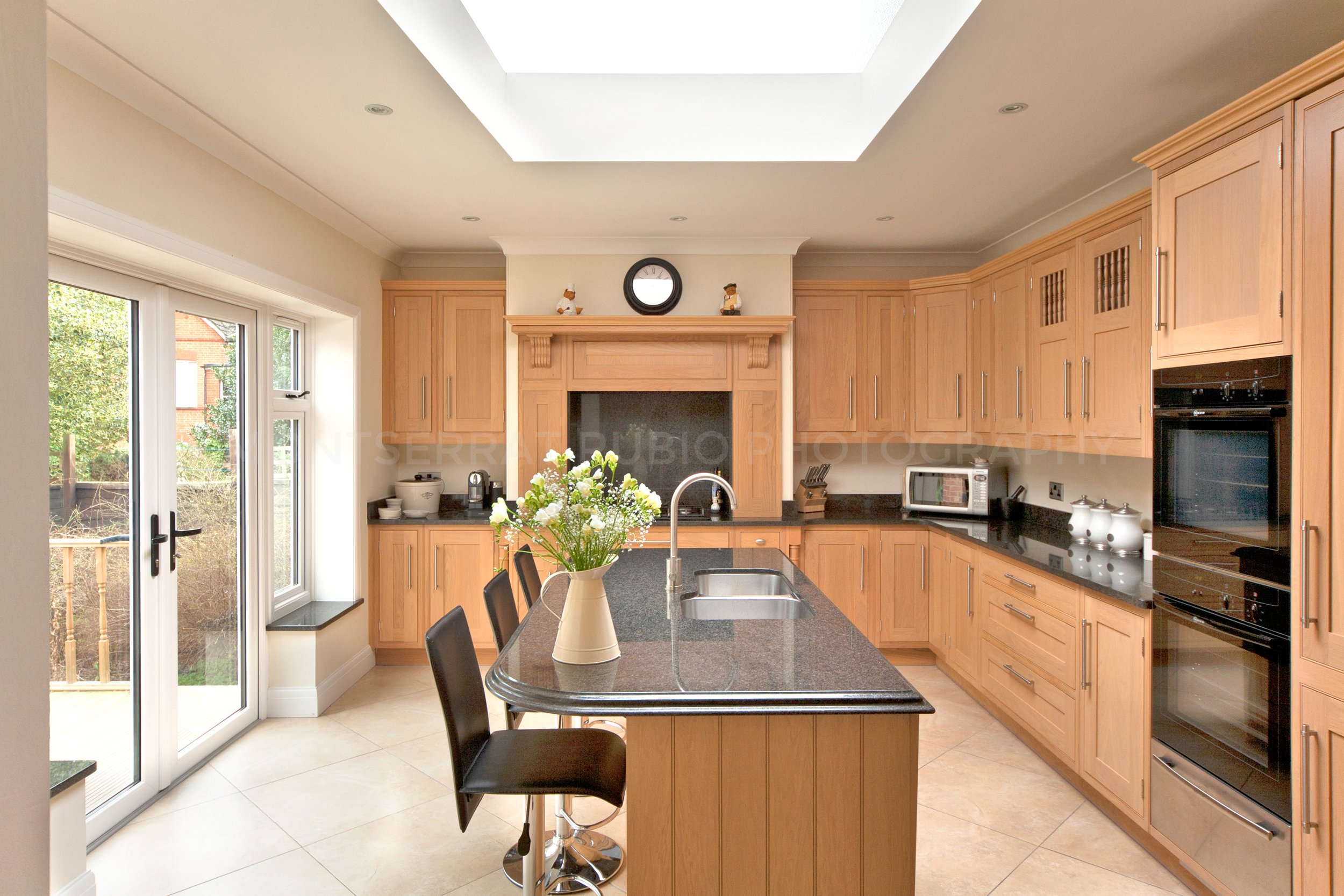 a contemporary kitchen with in honey wood cupboard and black worktop 