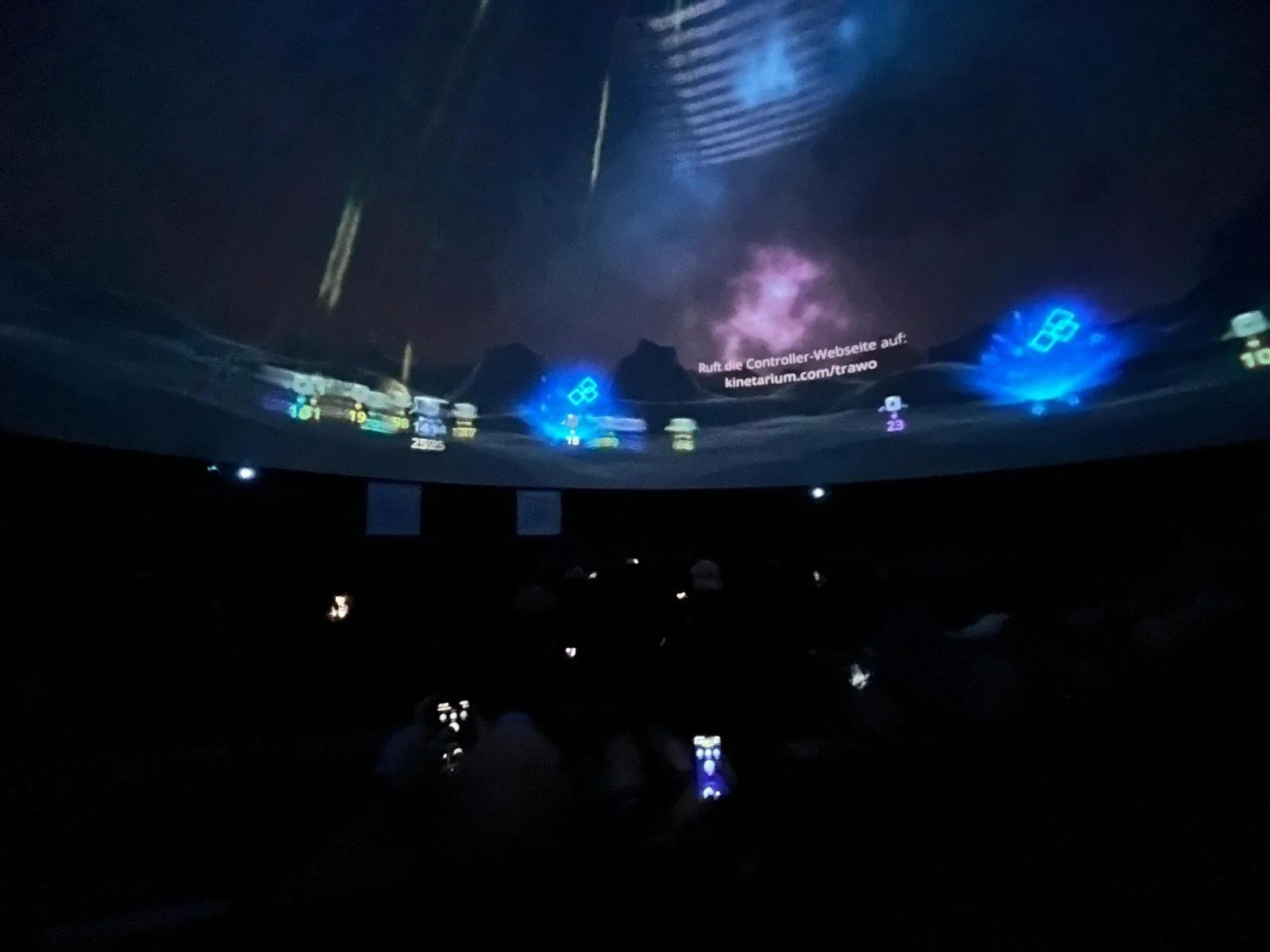 Besuchende der Travemünder Woche spielen mit Ihren Smartphones Dome Defenders in der mobilen Kuppel