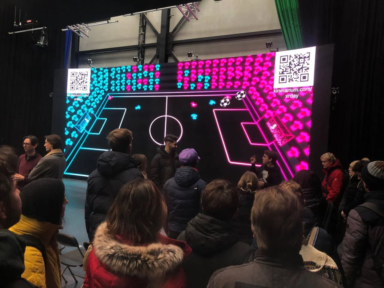 Besuchende spielen auf einem großen Bildschirm Soccer in der Cineplay-Version bei den XRDays