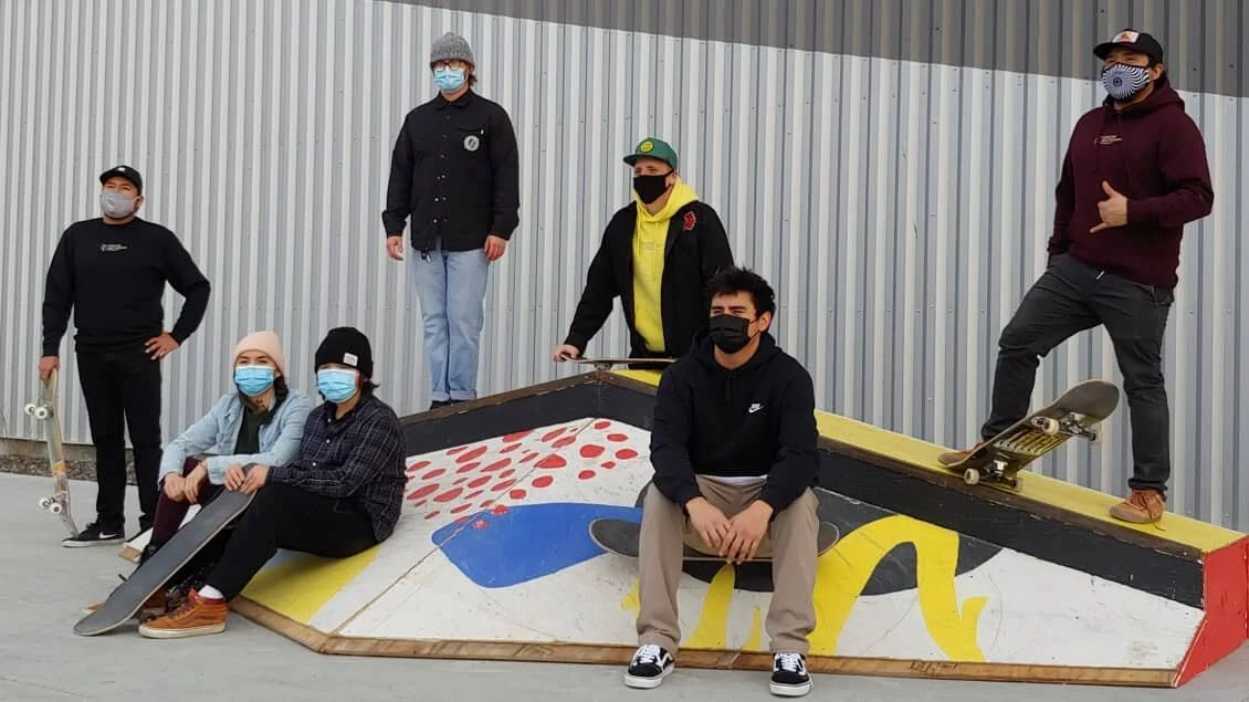 Group of masked skaters posing for a picture on a skate ramp.