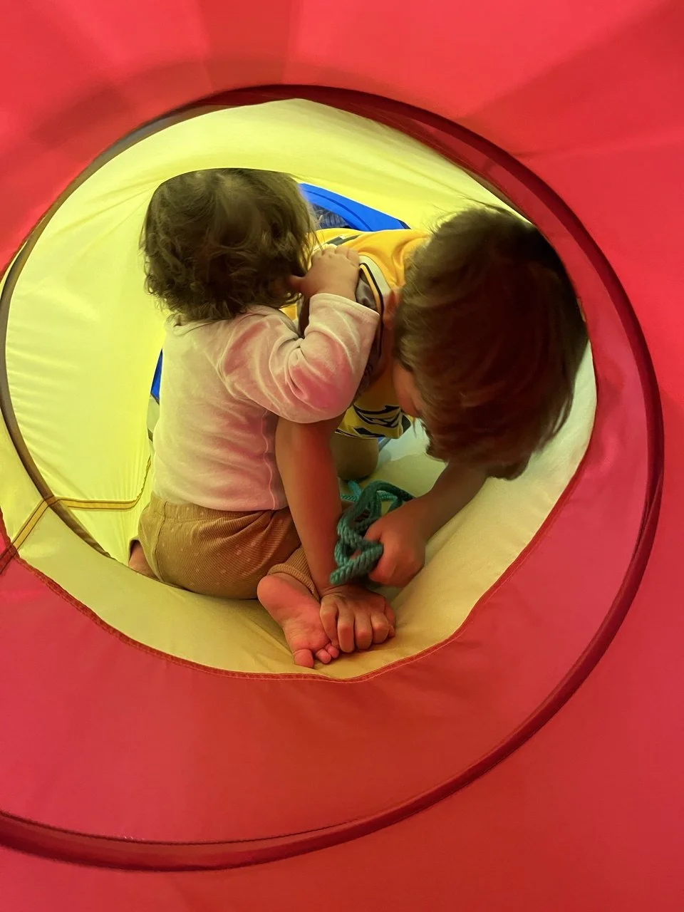 Zwei Kinder spielen in einem bunten Tunnel.