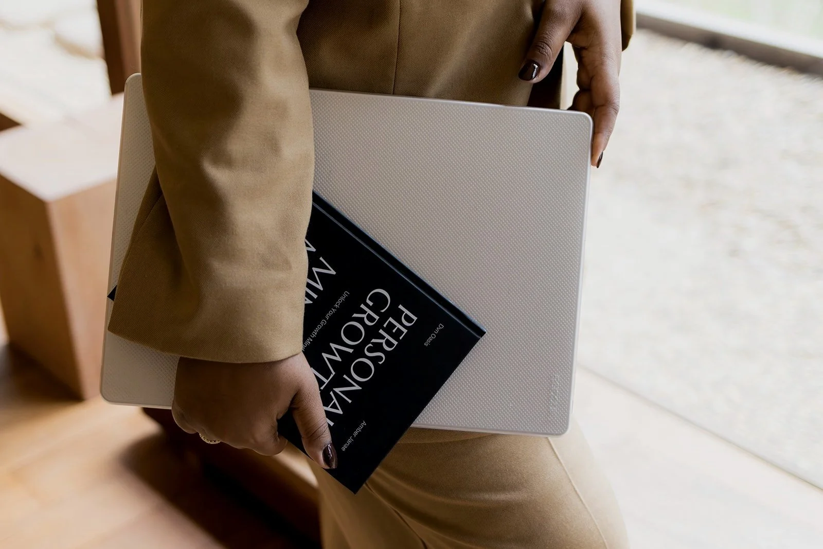 Person holding a closed laptop and a book titled 'Personal Growth'.