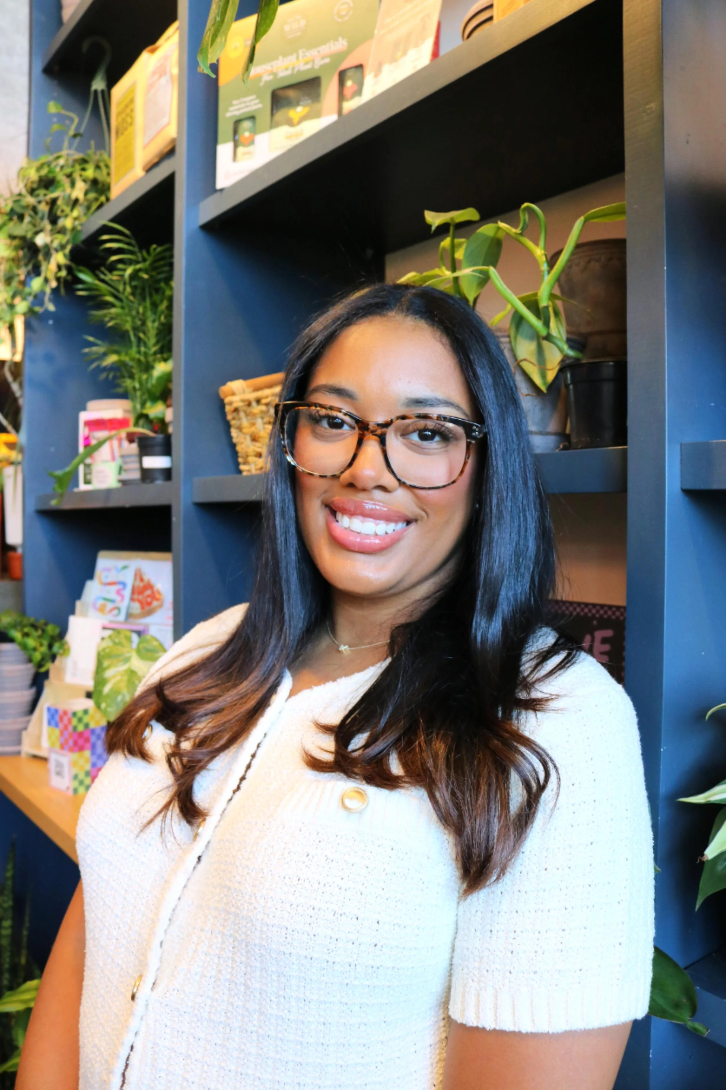 Black woman with glasses smiling for professional headshot photo in Greenhouse Jax Bar - plant bar in Jacksonville, FL - Female therapist of More Life Wellness - Mental Health resources of Jacksonville, FL.
