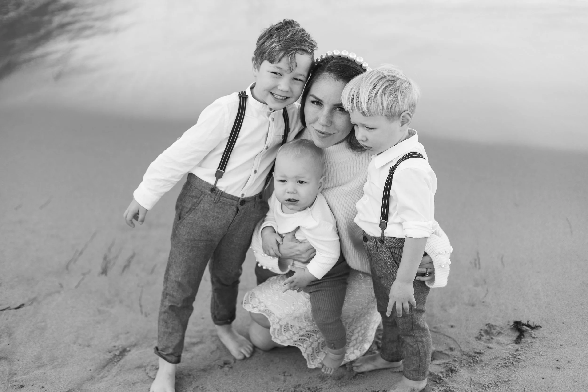 A woman with four young children on a sandy beach.