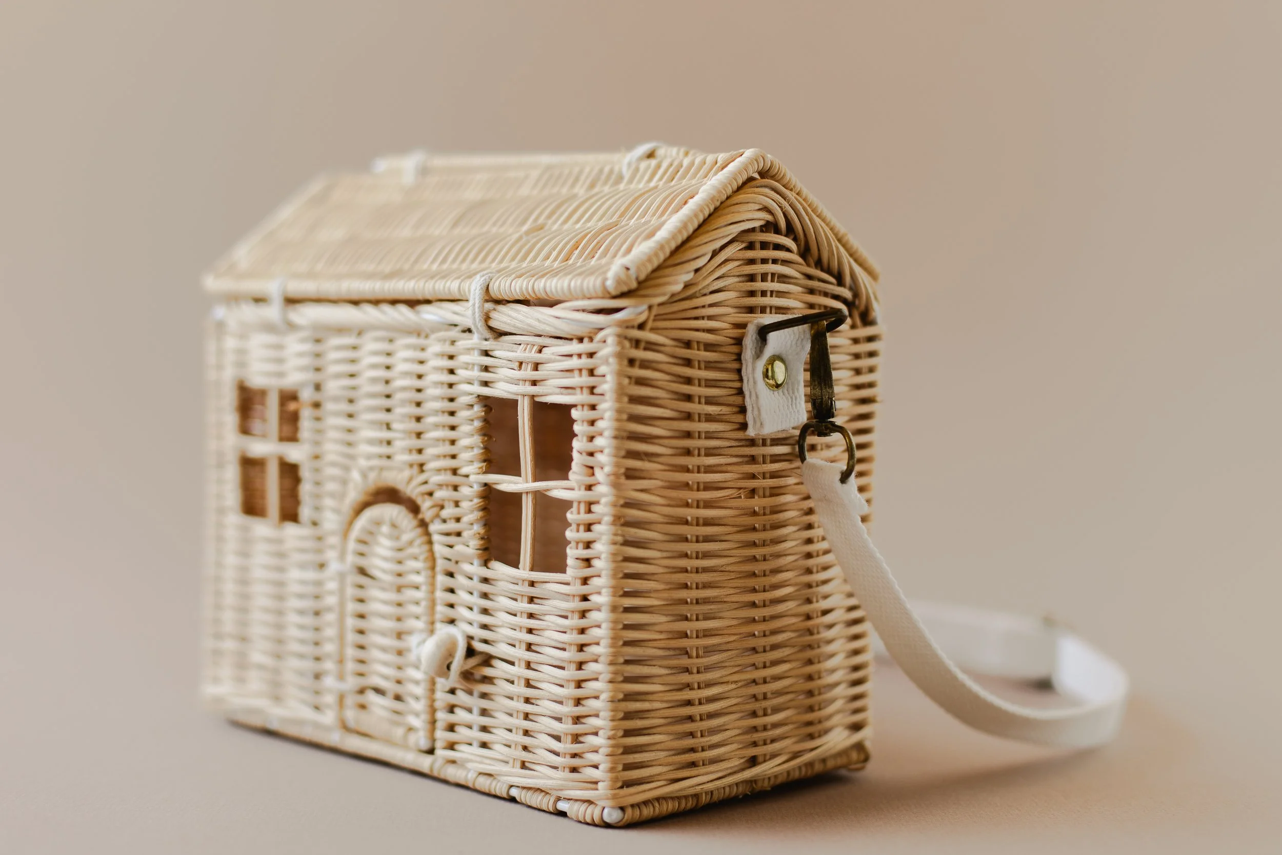 Small woven wicker house-shaped handbag with a strap and metal latch.