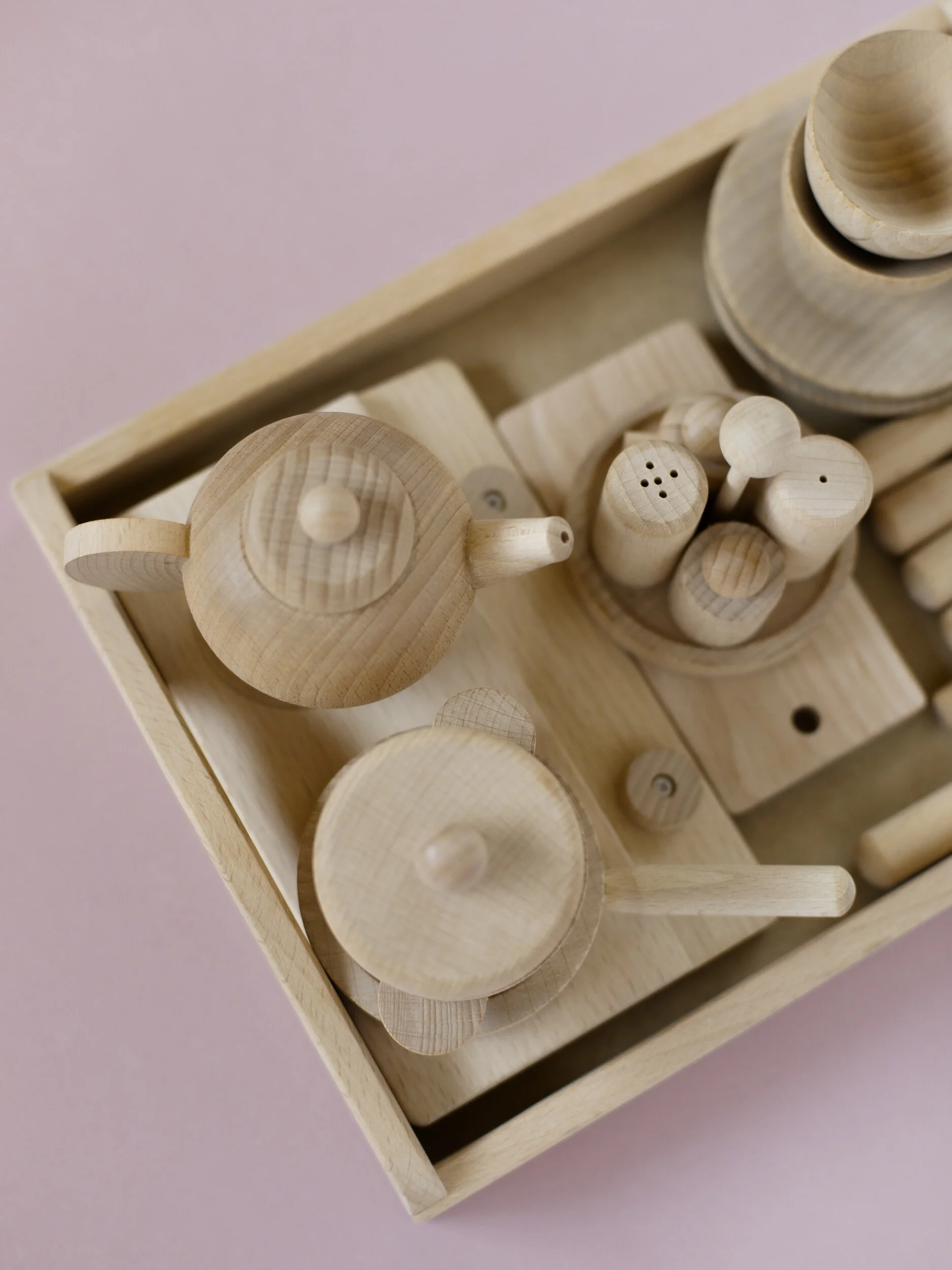 Wooden toy tea set including teapot, cups, and utensils in a wooden box.