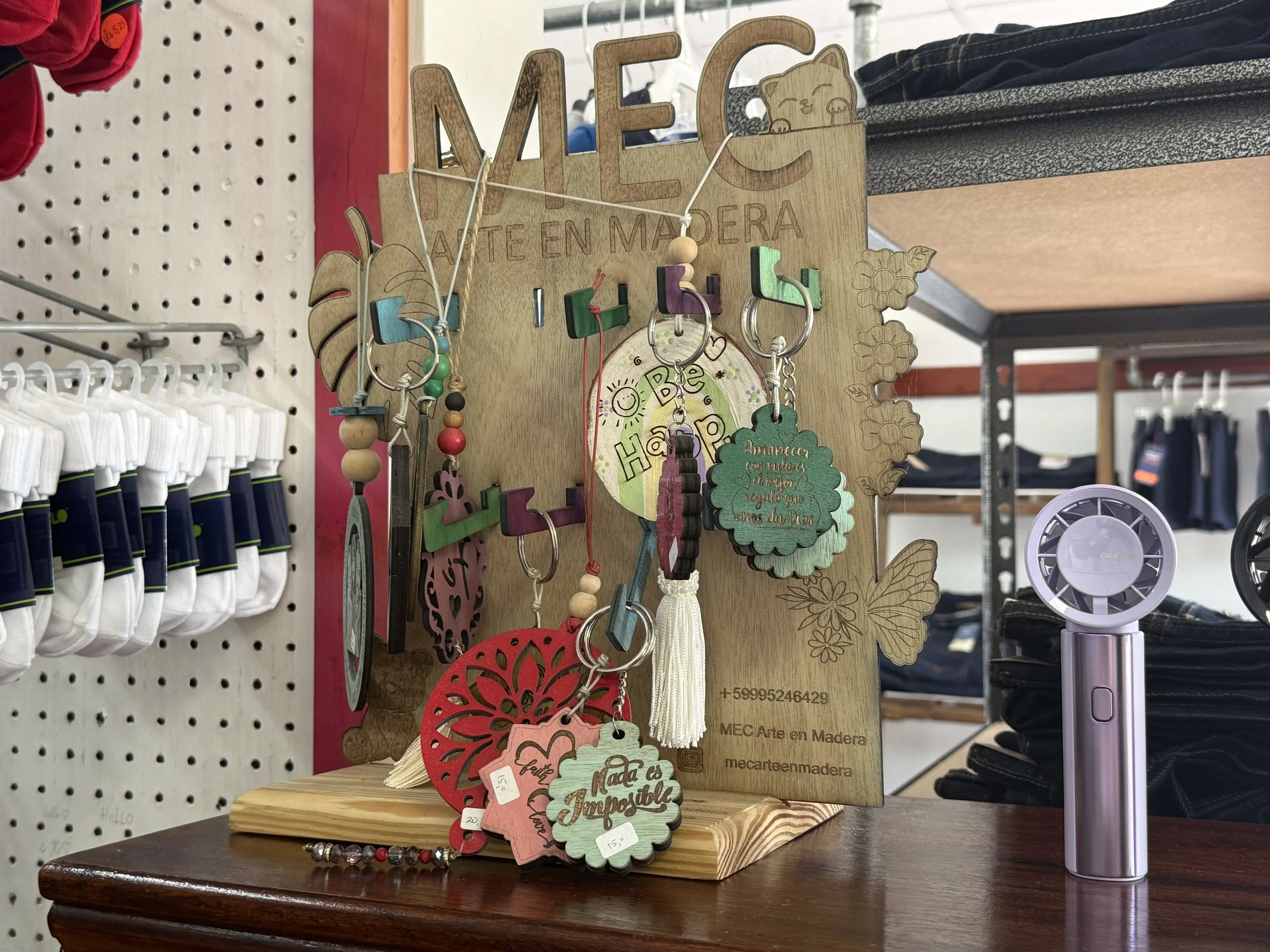 Wooden display board with various handmade items including keychains and decorative tags.