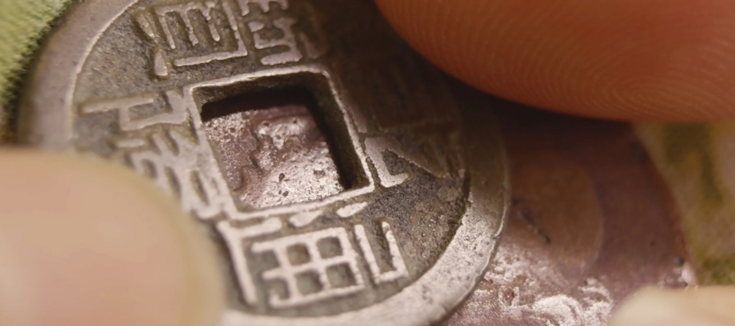 Image: Cindy Yuen-Zhe Chen, Dismantle / Assemble, 2026. Close up of fingers touching a Chinese coin (Guangning).