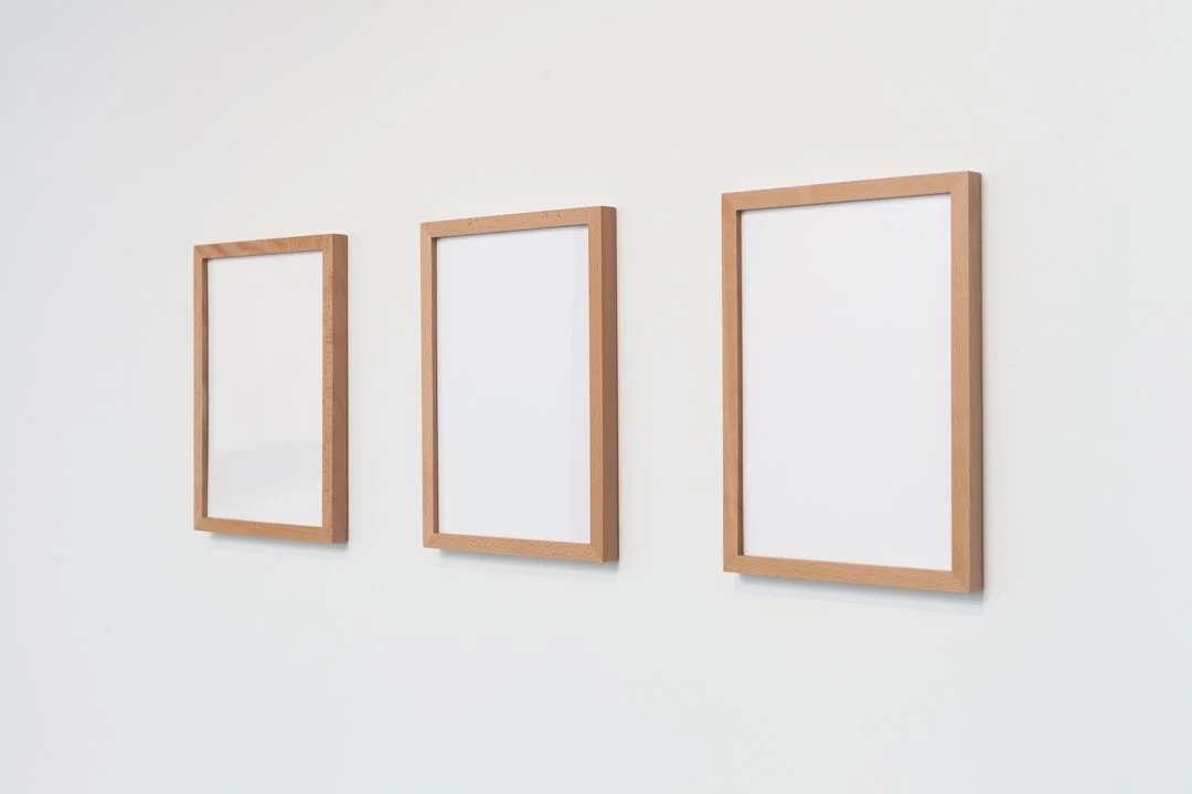 3 blank wooden frames on a white wall.