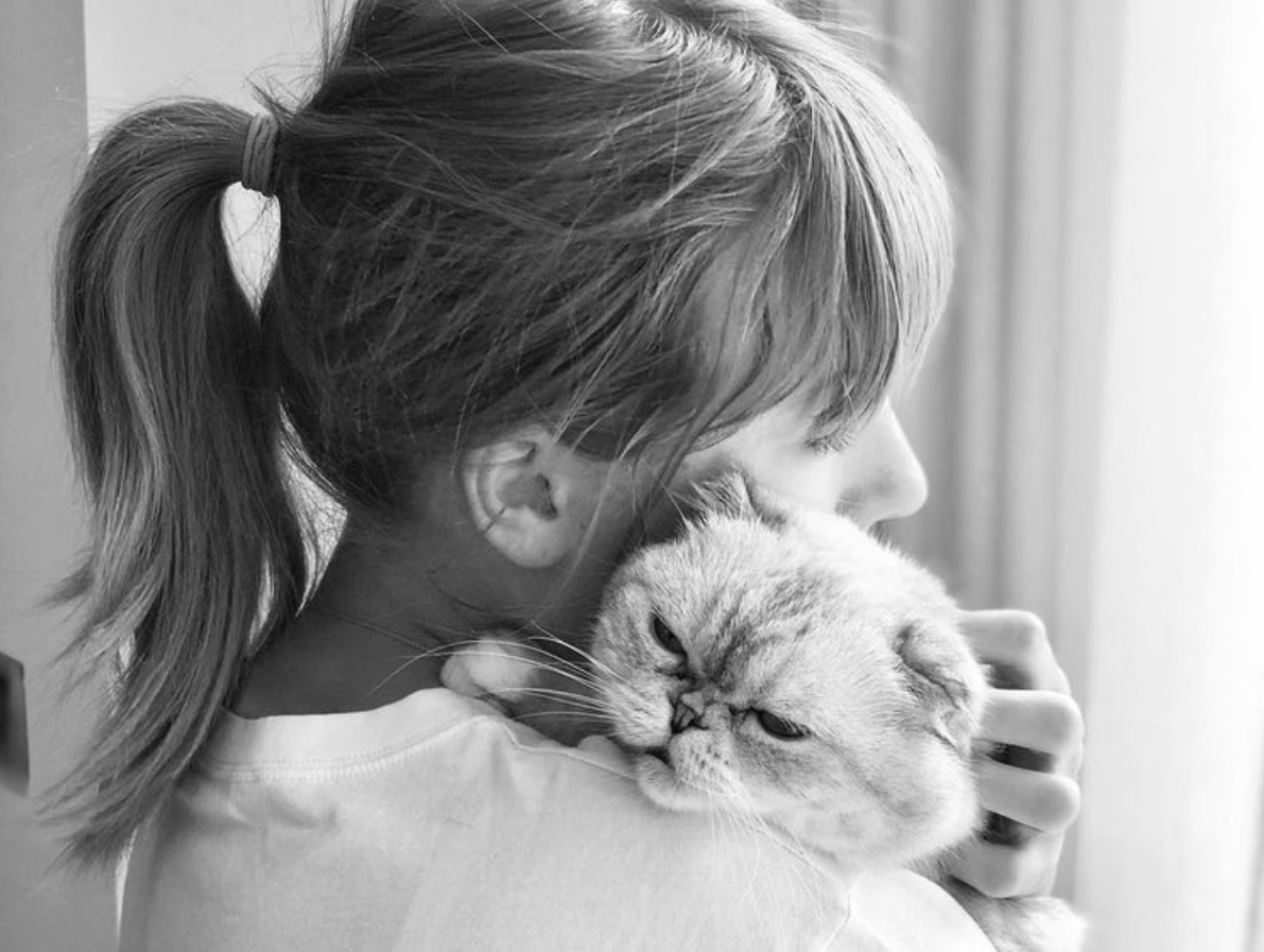 Black and white photo of Taylor Swift hugging her cat Olivia Benson