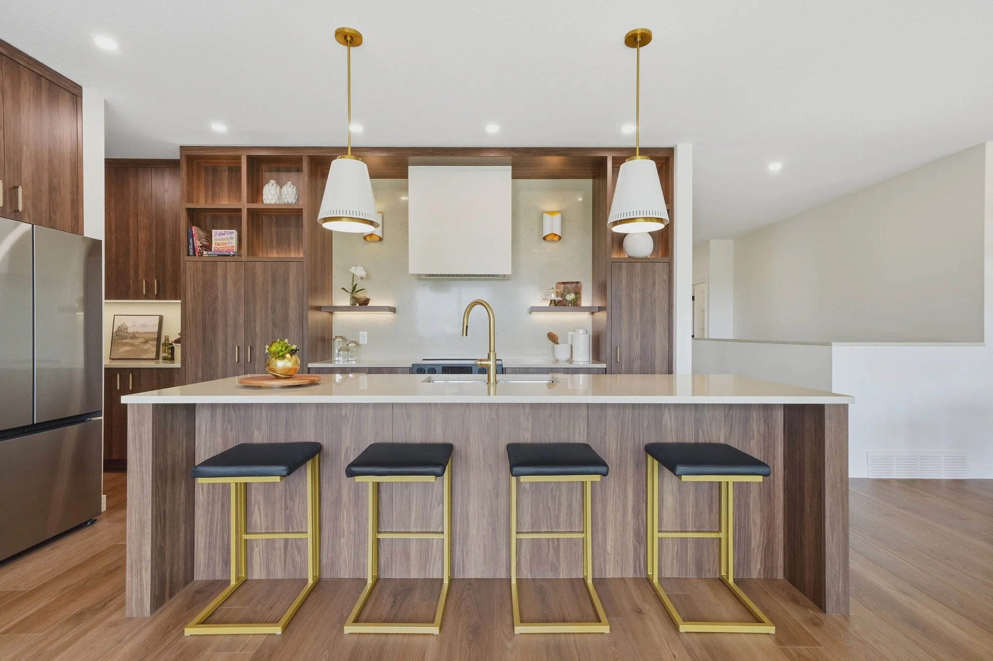 Contemporary Saskatoon kitchen with a waterfall island, dark wood cabinetry and four gold-framed stools.