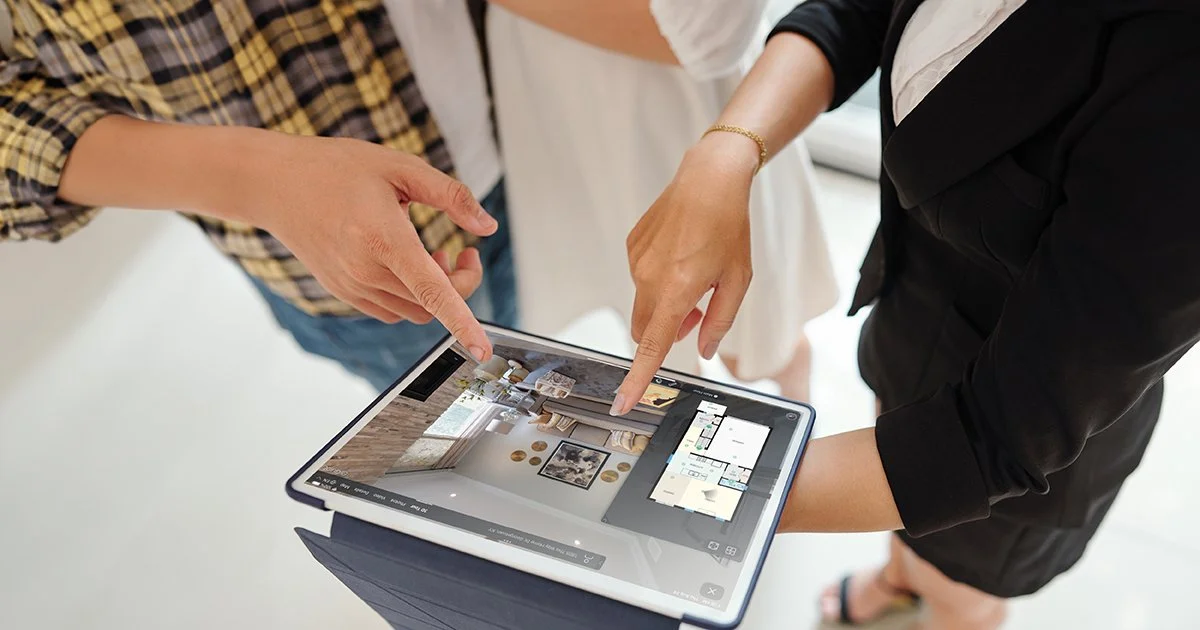 Realtor and homeowners reviewing an interactive 3D tour on a tablet during a listing presentation
