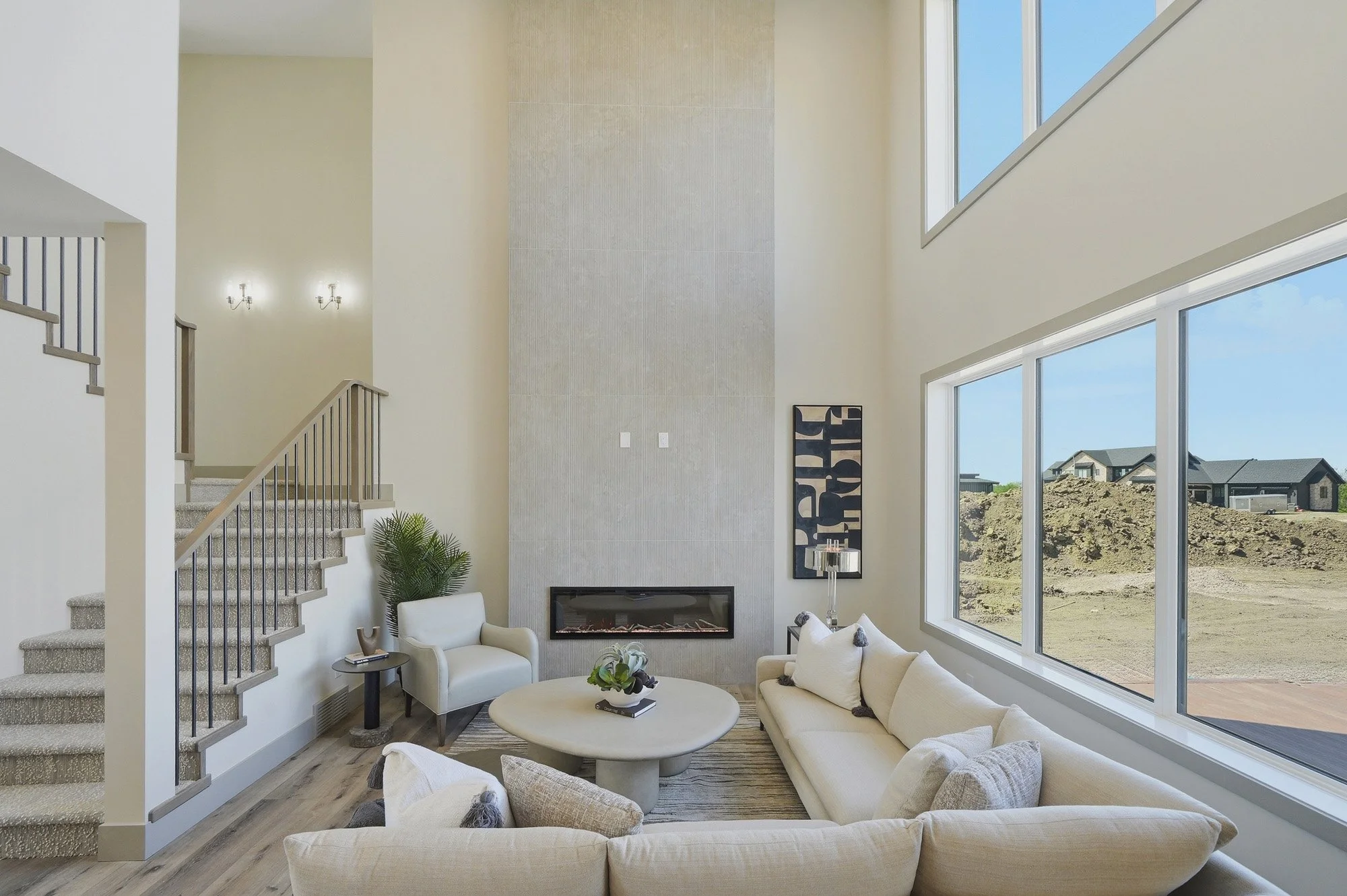 Two-storey living room with a dramatic feature wall, linear fireplace, large windows and neutral furnishings