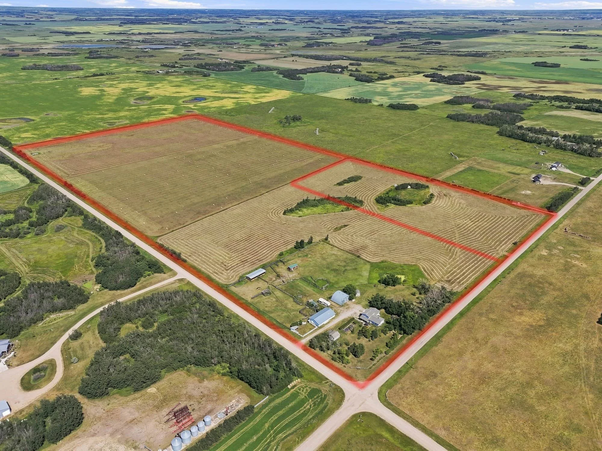 Aerial view of a large farm property outlined in red, with fields, buildings, and surrounding green farmland.