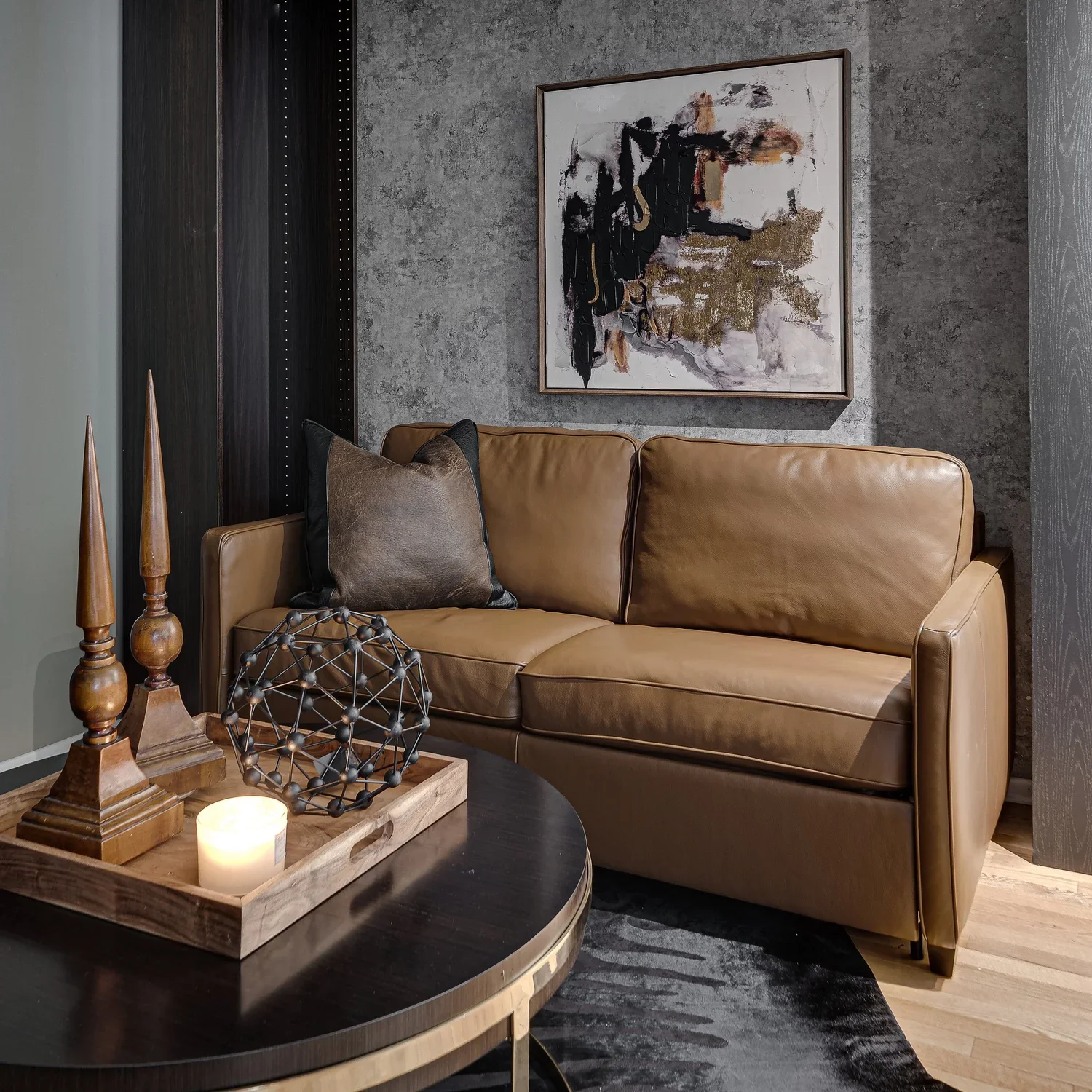 Brown leather sofa beneath abstract artwork in a textured modern sitting room.