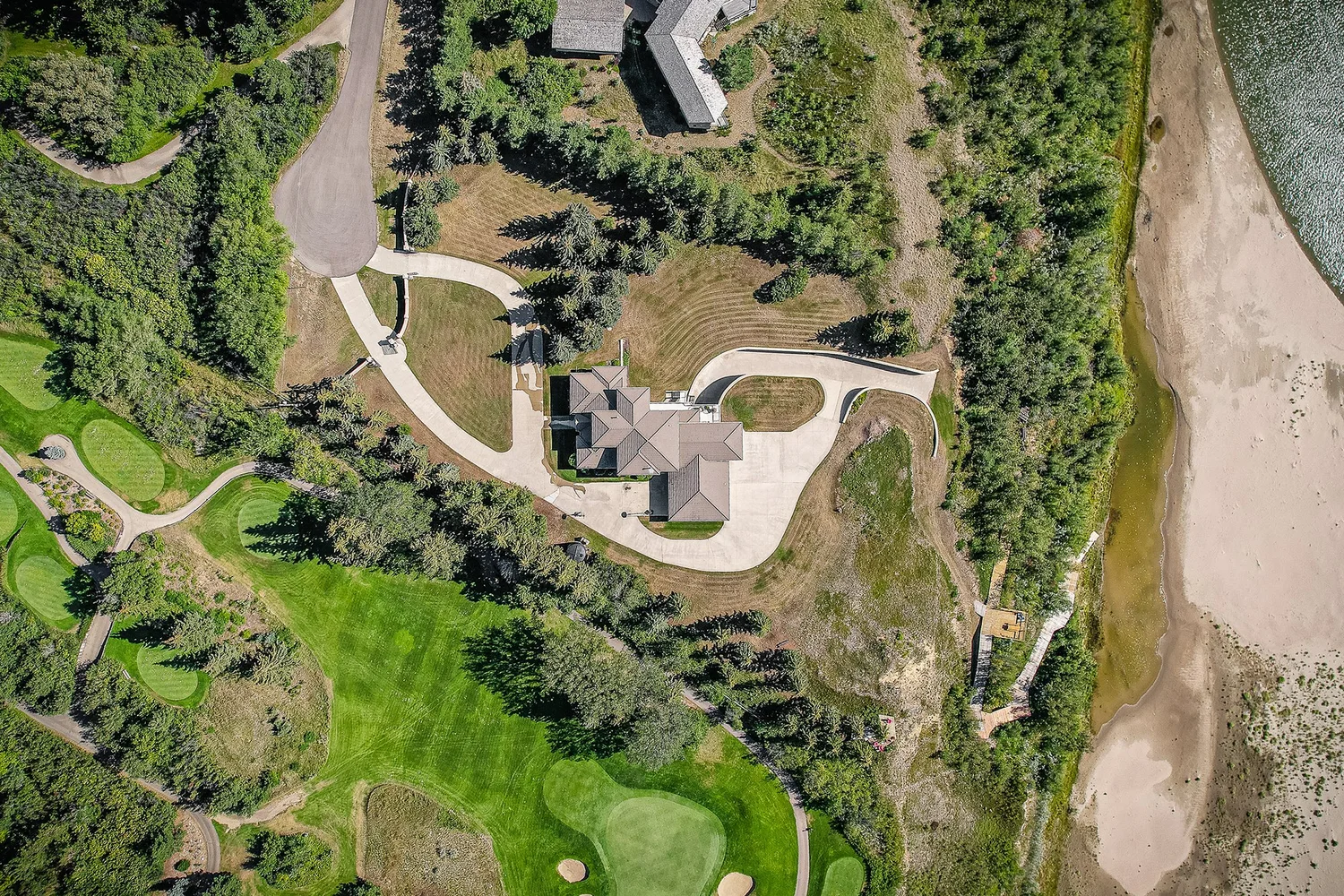 Aerial drone photograph of an acreage with fields, trees, outbuildings and access