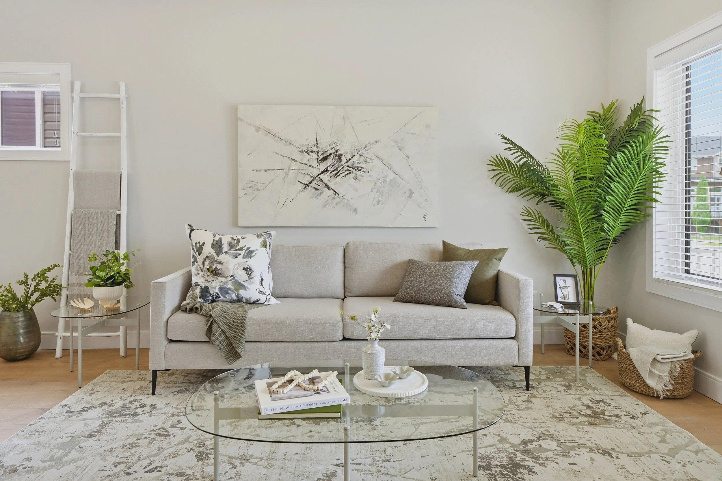 A modern living room, perfect for real estate photography Saskatoon, featuring a beige sofa, abstract art, and a glass coffee table.