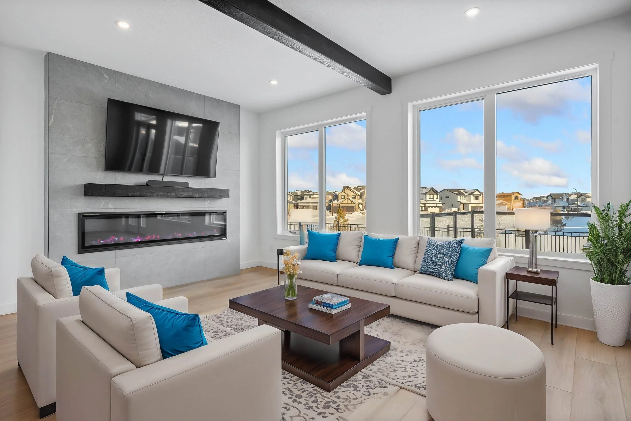Modern living room with white sofas, blue pillows, a fireplace, and large windows—perfect for stunning real estate photography.
