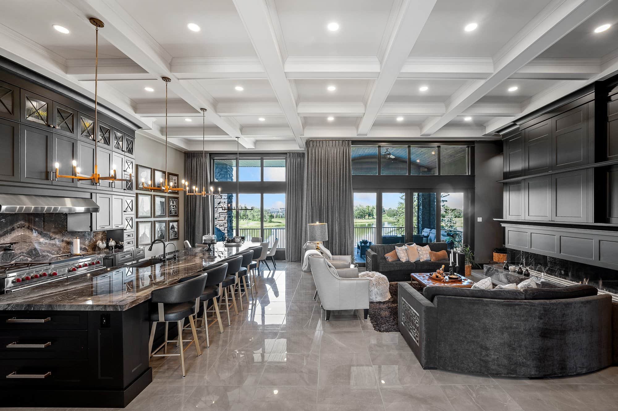 Modern open-concept kitchen and living room, showcased with luxury real estate photography, features dark cabinetry and marble floors.