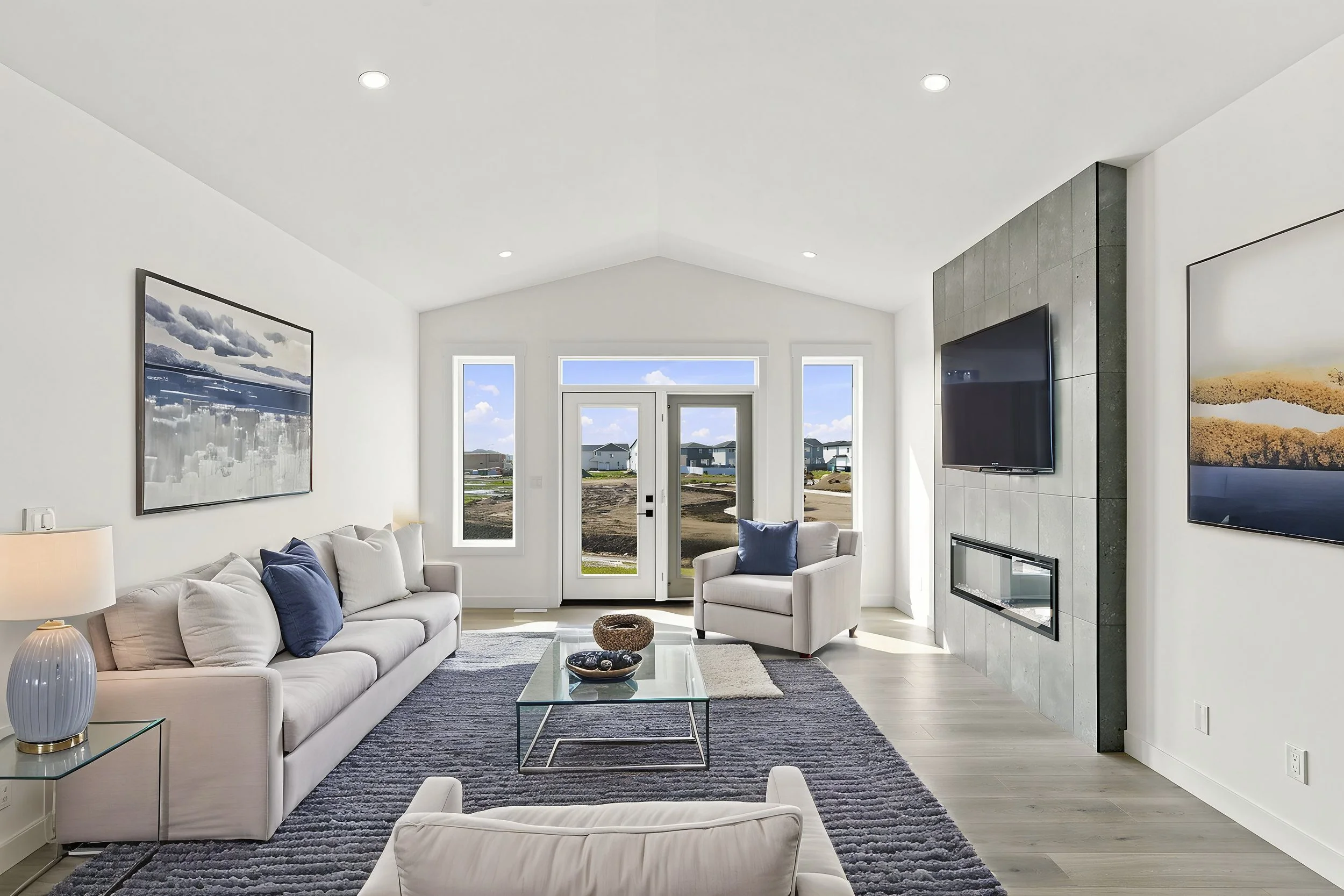 Bright professionally photographed living room with large windows and a modern fireplace