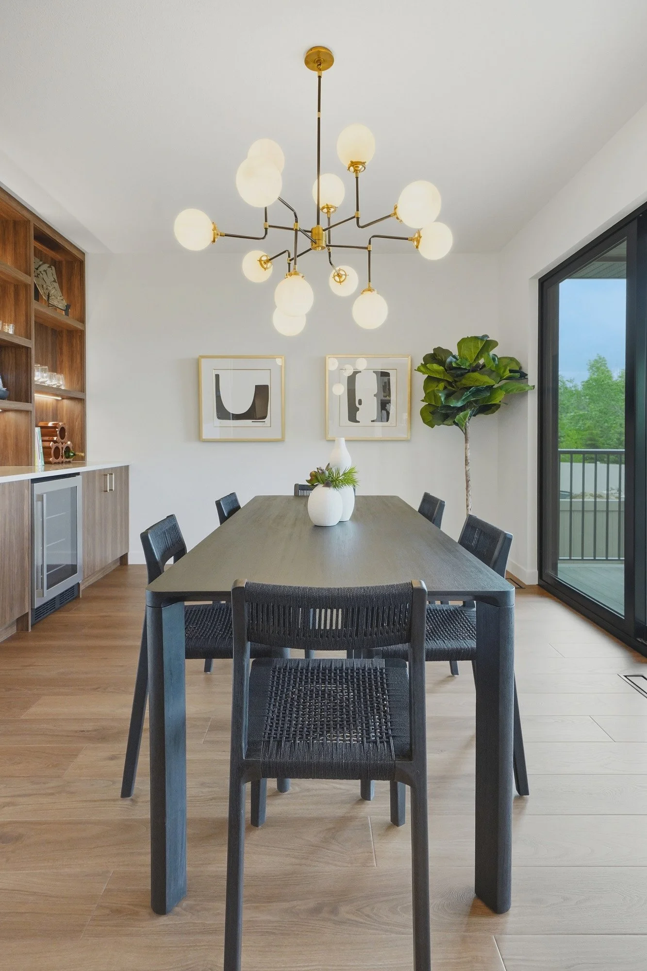 Modern dining room with black table, six chairs, gold chandelier, wall art, and large windows—perfect for real estate photography Saskatoon.