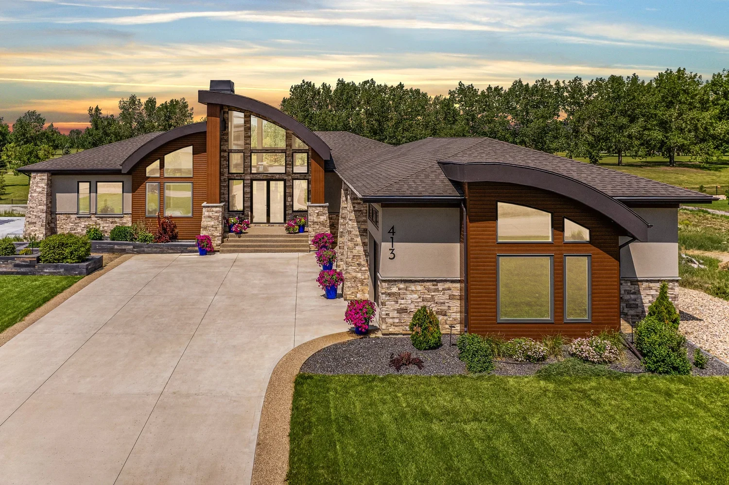 Aerial view of a luxury home at twilight surrounded by mature trees and landscaped grounds.