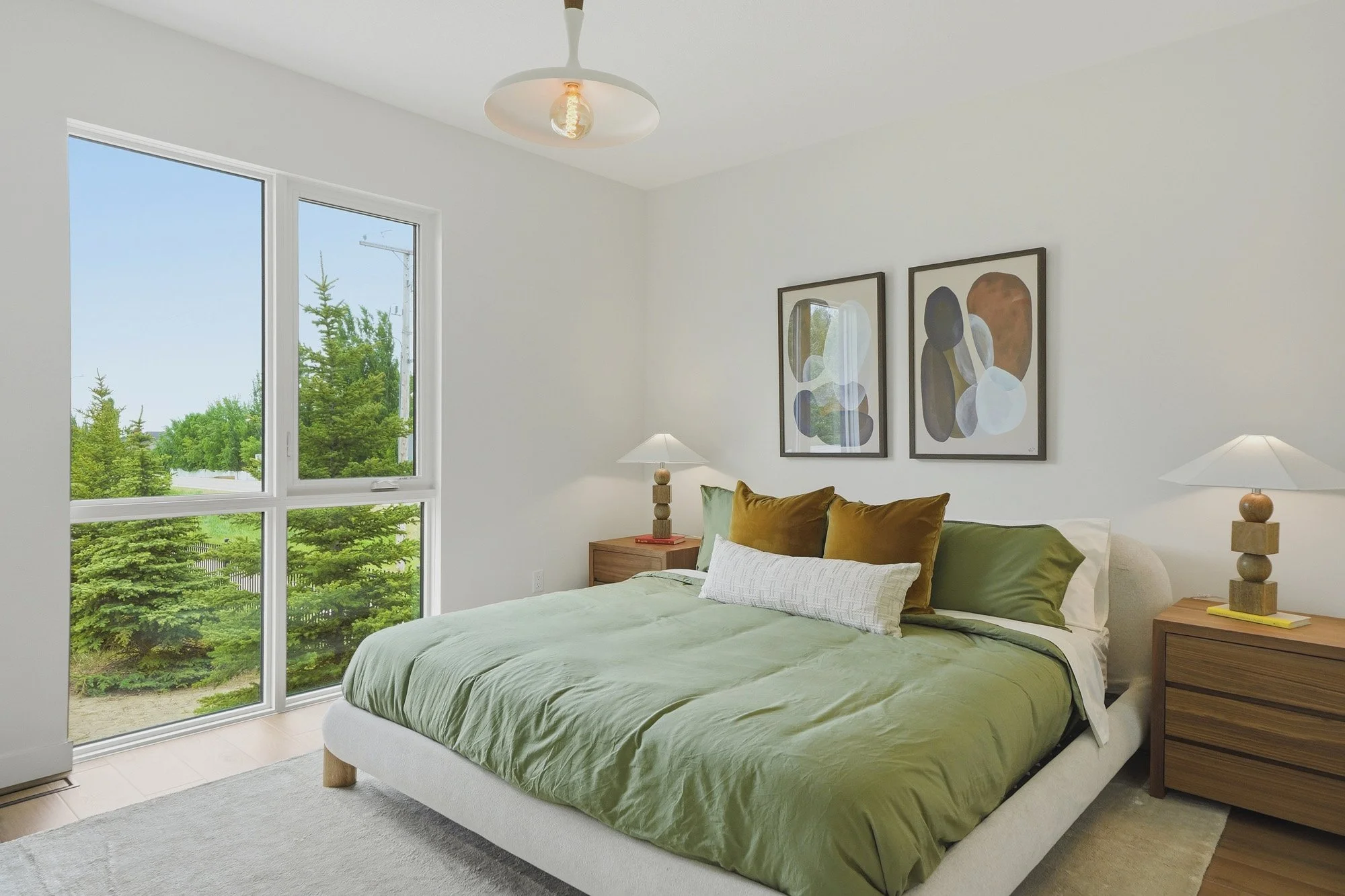 Bright bedroom with green bedding, abstract art, and large windows. Perfect for real estate photography Saskatoon listings.
