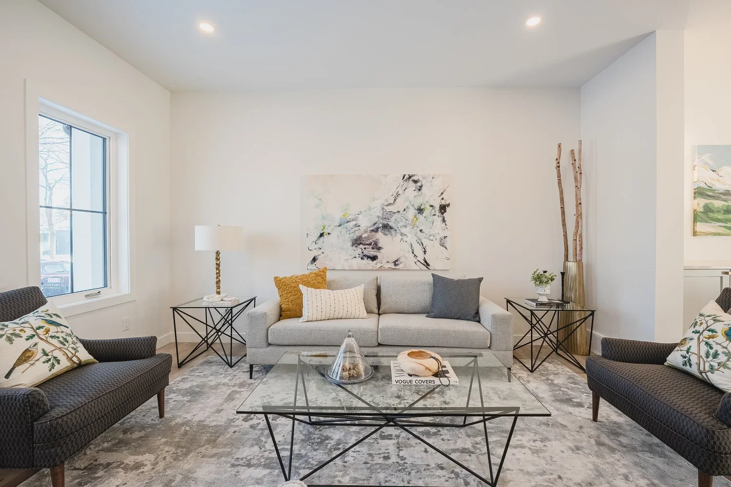 Staged living room with grey sofas, gold accent pillows and a soft grey area rug.