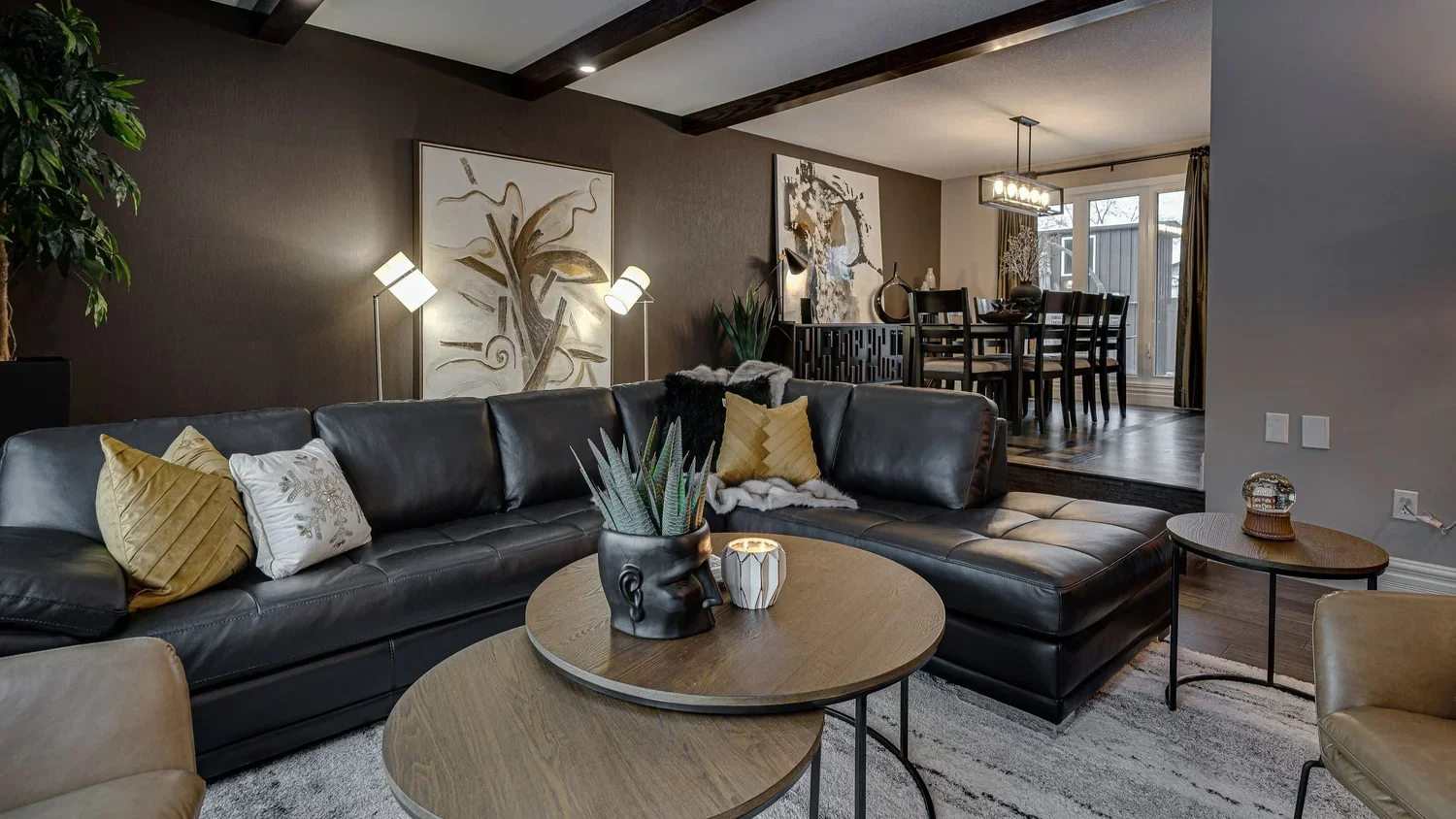 Moody modern living room with black leather sectional and raised dining area.