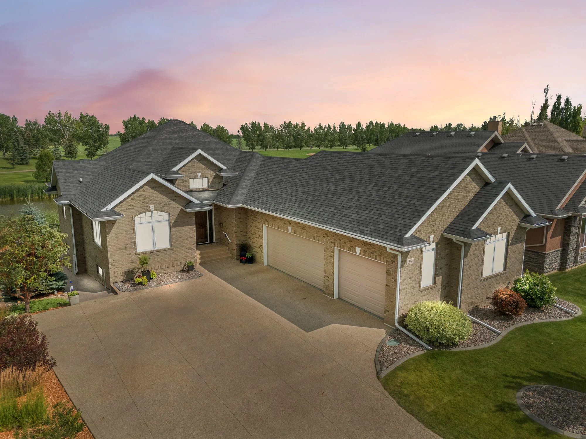 Single-story brick house with three-car garage, landscaped yard, and a virtual twilight photo of a home at sunset.