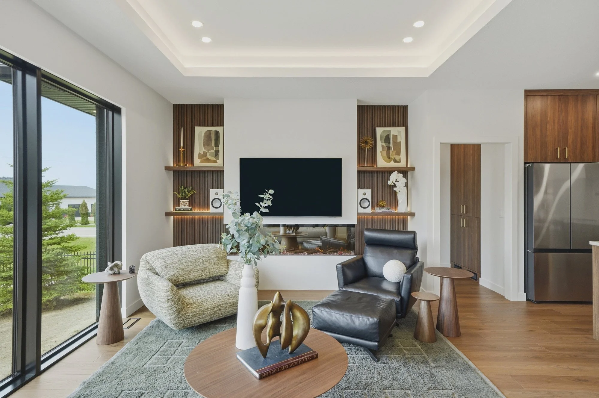 Modern living room with large TV, stylish chairs, wood accents, and plants—perfect for real estate photography Saskatoon listings.