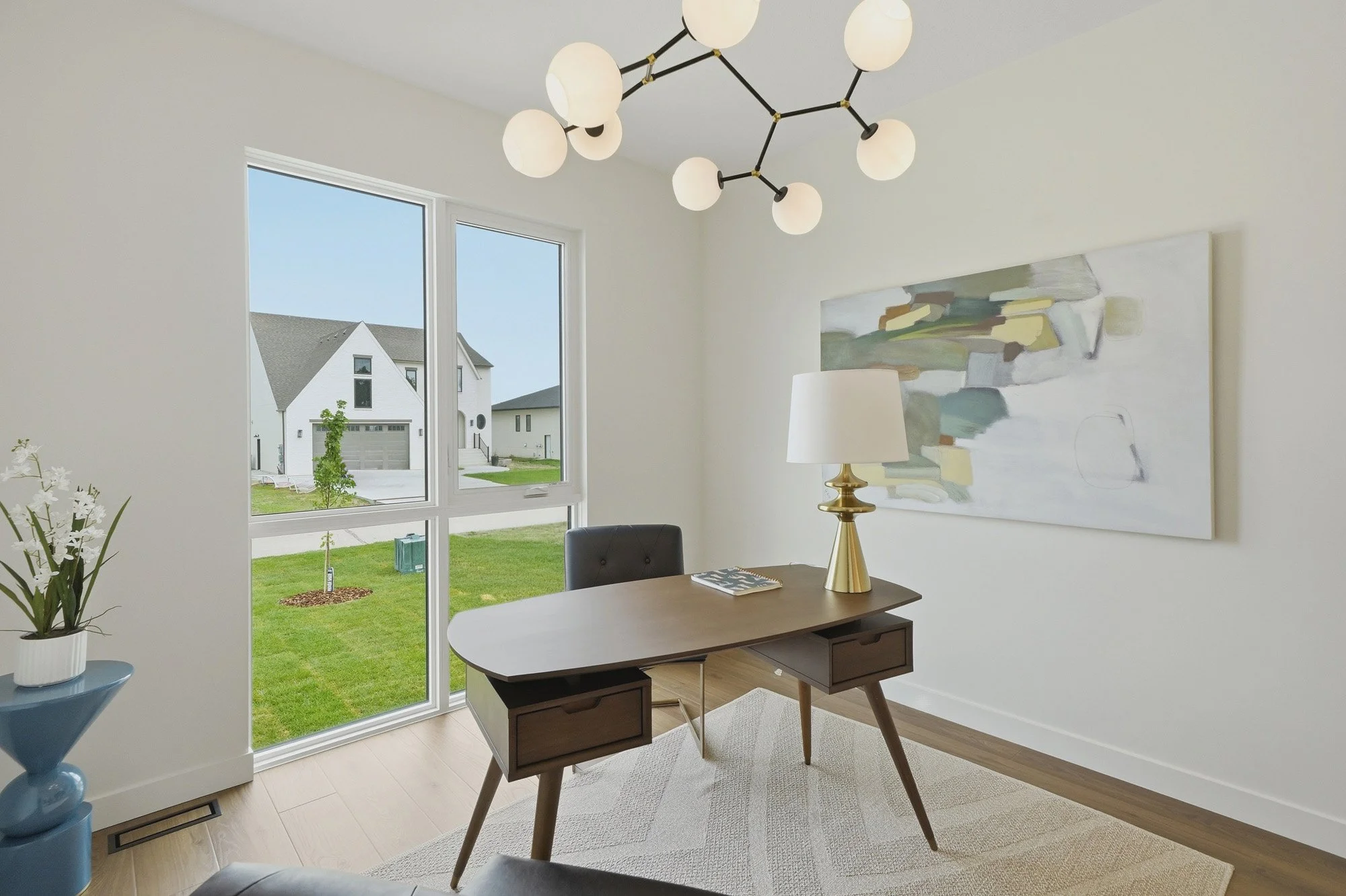 Modern home office with large window, abstract art, unique chandelier—perfect for real estate photography Saskatoon professionals.