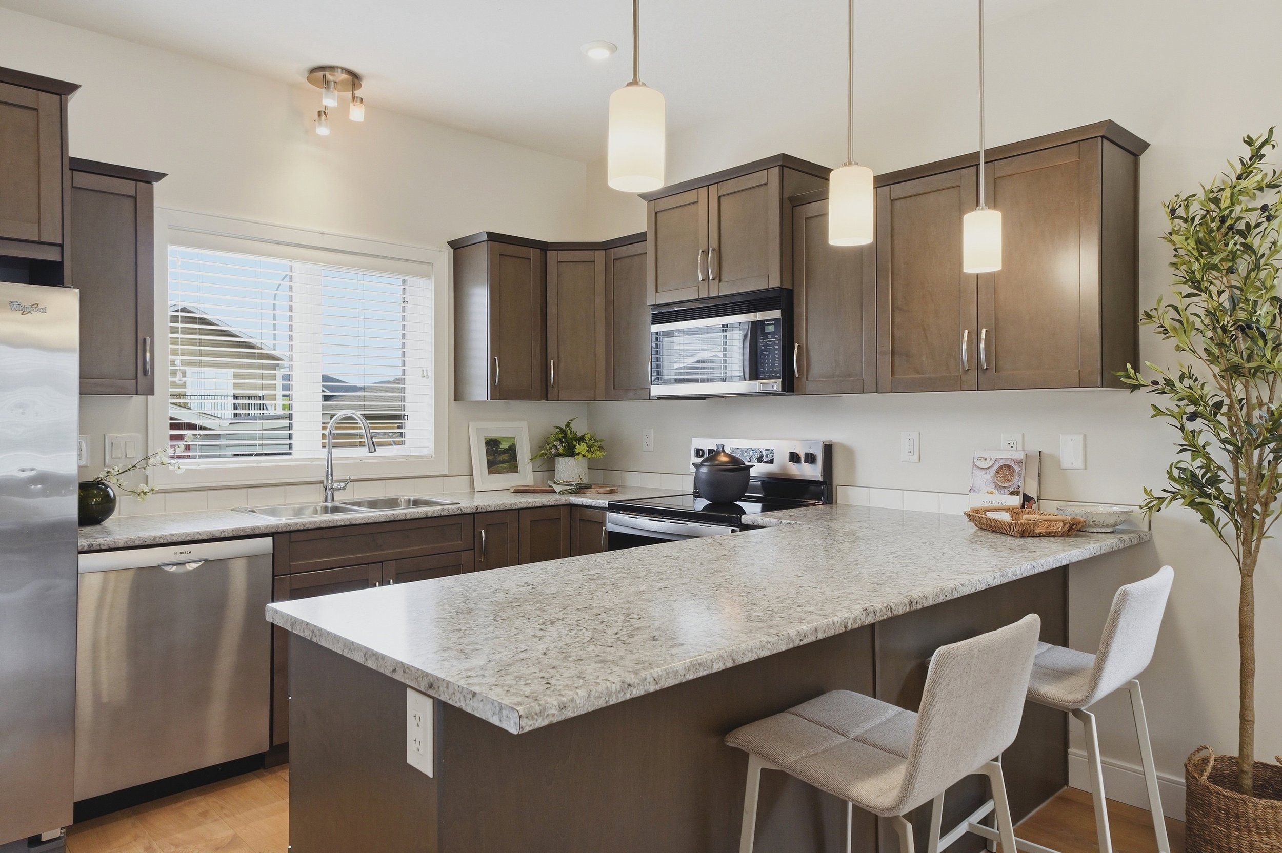 Modern kitchen with brown cabinets, marble island, and stainless appliances—perfect for real estate photography Saskatoon.
