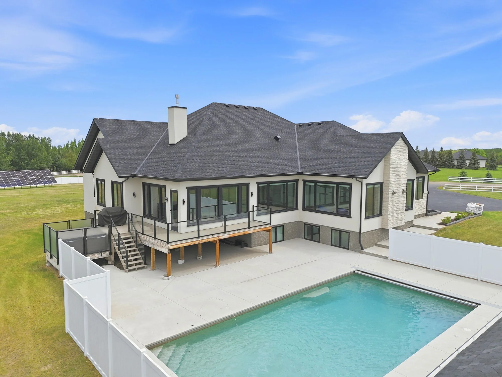 Elevated aerial view of a luxury home with a swimming pool, spacious deck and landscaped backyard