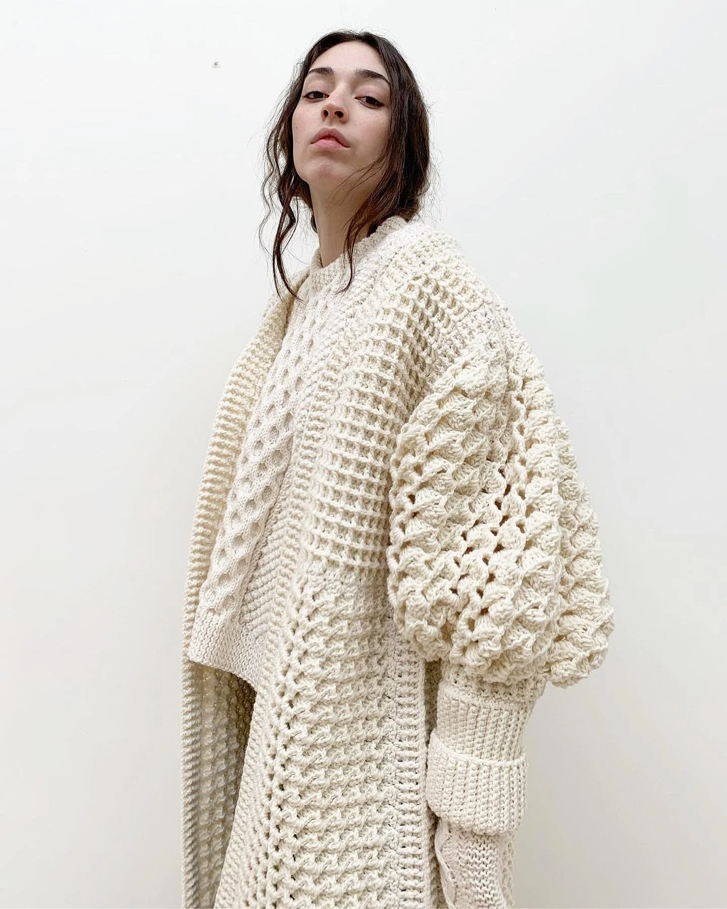 Hand crochet coat lauded with hand knit Aran sweater, shot in studio.